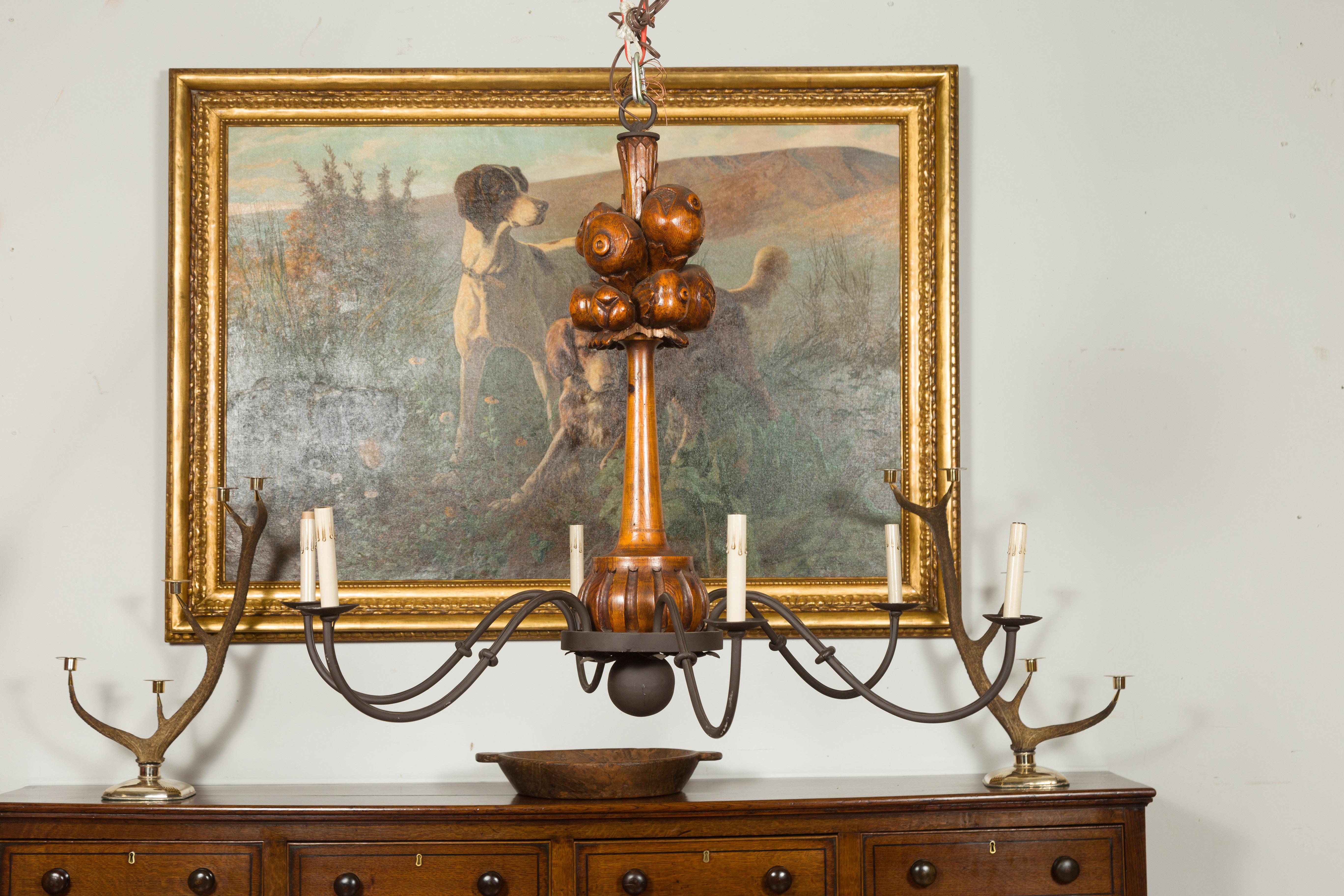 A pair of large English carved oak or pine six-light chandeliers from the early 20th century, with fruit motifs and swooping arms. Created in England during the first quarter of the 20th century, each of this pair of chandeliers attracts our