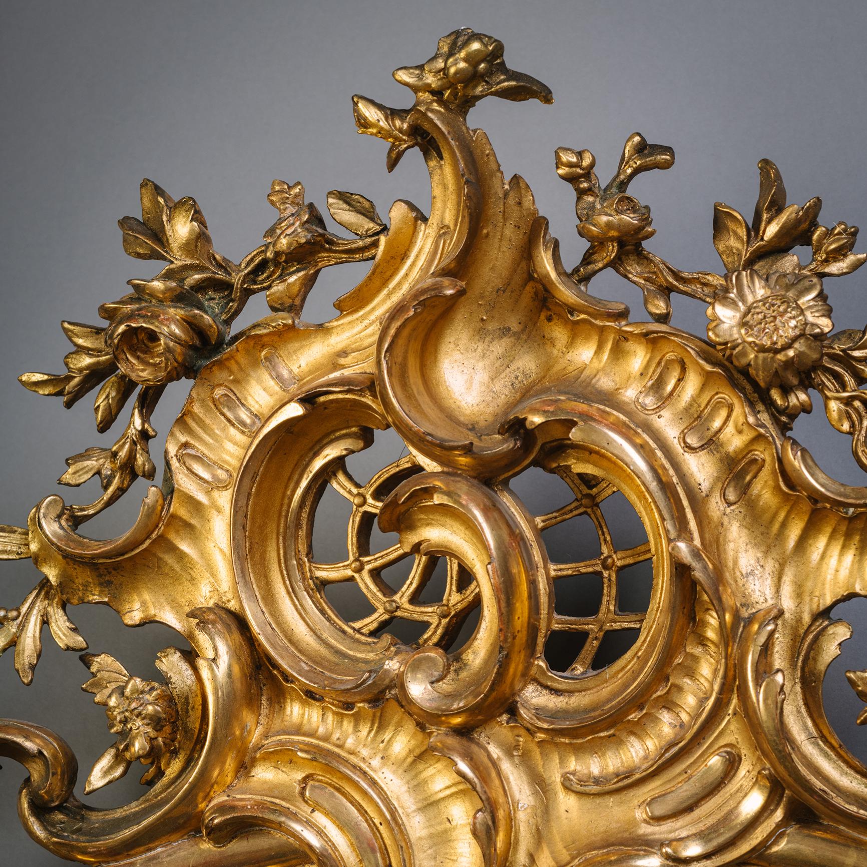 Rare et grande paire de miroirs muraux en bois doré en forme de cartouche de Florentine.

Chacune d'elles est surmontée d'une rocaille ouvragée, ornée de coquillages et de fleurs. Le site  cadre entourant le plateau en forme de cartouche avec