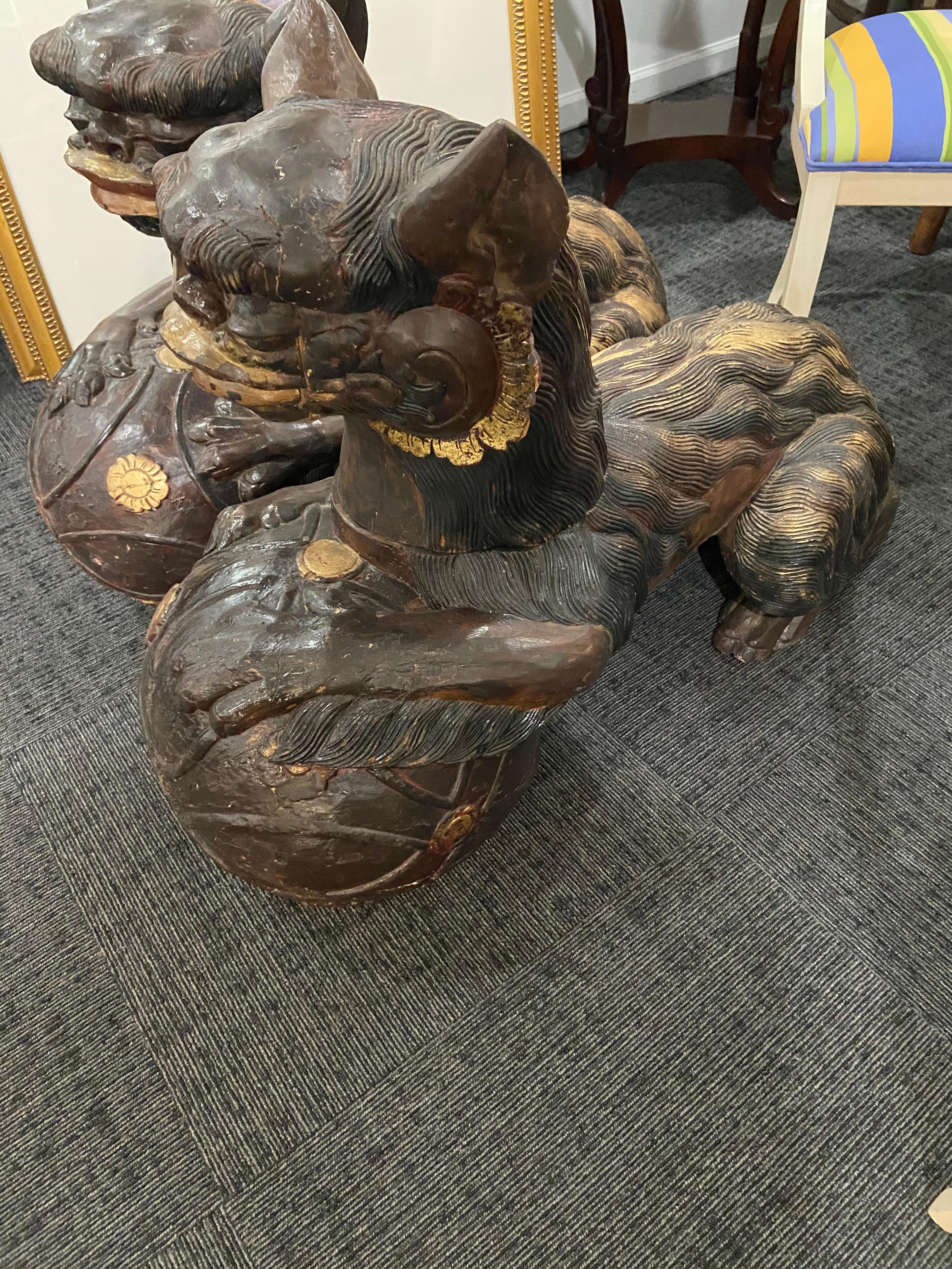 Large pair of foo dogs in the Chinese Style. Early 20th century or earlier. Carved from solid wood coming apart in 2 pieces. Heads are removable.  Approximate size 40” length 16” wide and 30” tall.