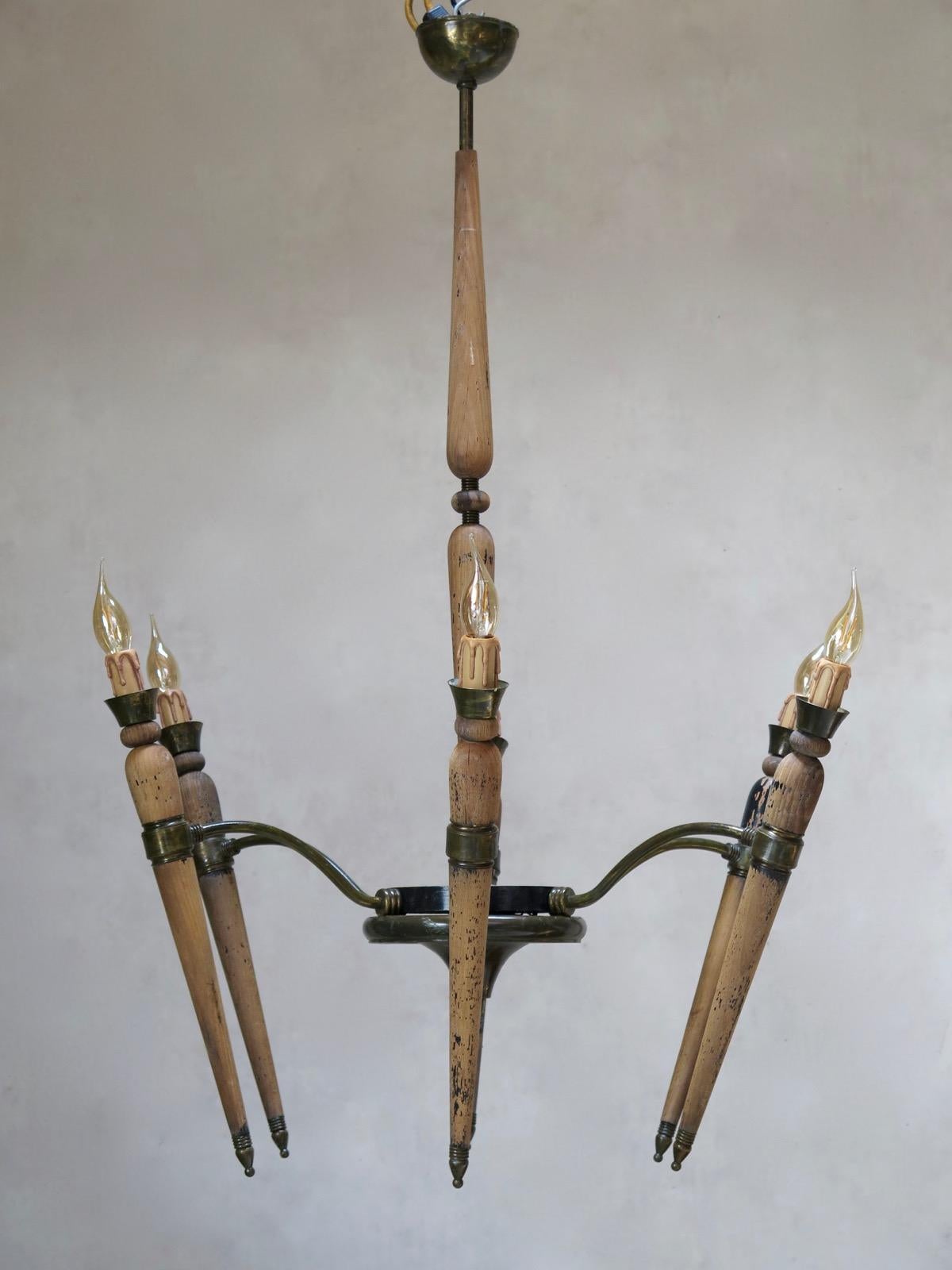 Unusual and very chic pair of large-sized French Art Deco chandeliers, with six torchere-shaped lights each. The wood originally had a glossy black finish, but the paint has largely worn off.