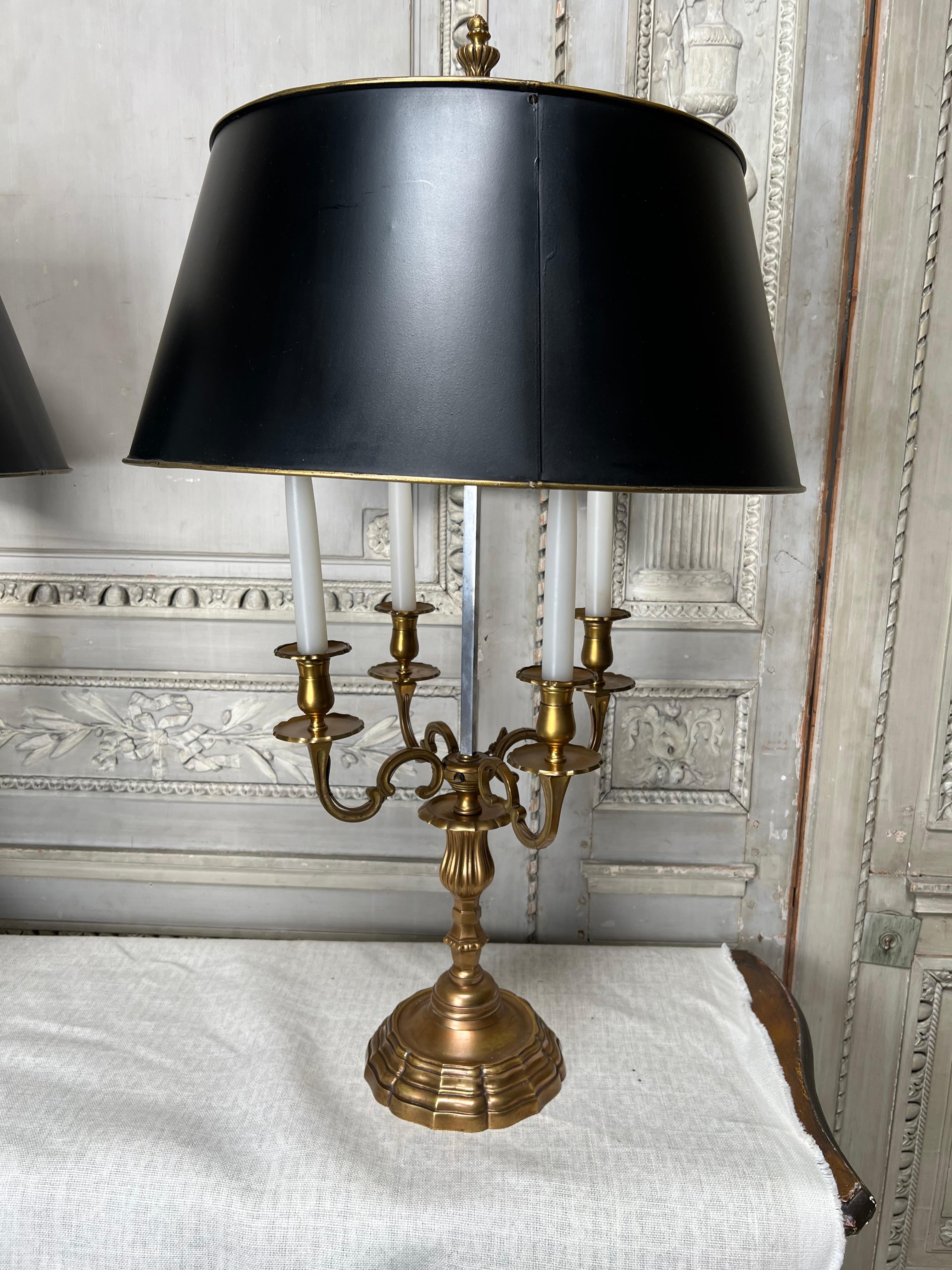 A very large pair of French neoclassical style bouillotte lamps with adjustable tole shades painting in black. These Fine lamps are highly decorative and functional. 
They are currently not wired but can be professionally wired for an additional