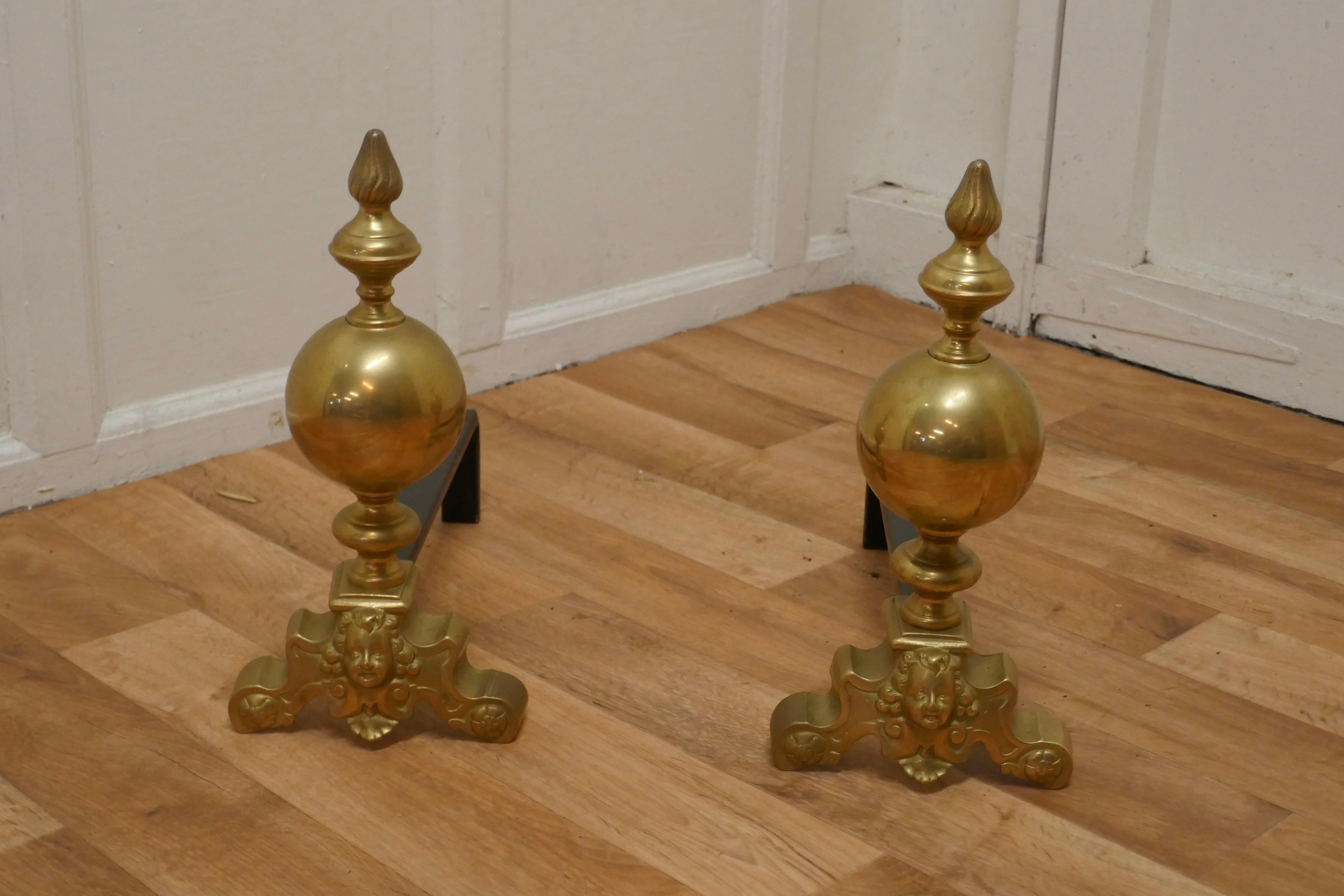 Large pair of French brass andirons, fire dogs or chenets

This is a Large globe shaped pair of Brass Andirons they are decorated with Gothic faces in the centre of the large scroll feet
 
The Andirons are 15” high, 18” wide at the front and 16”
