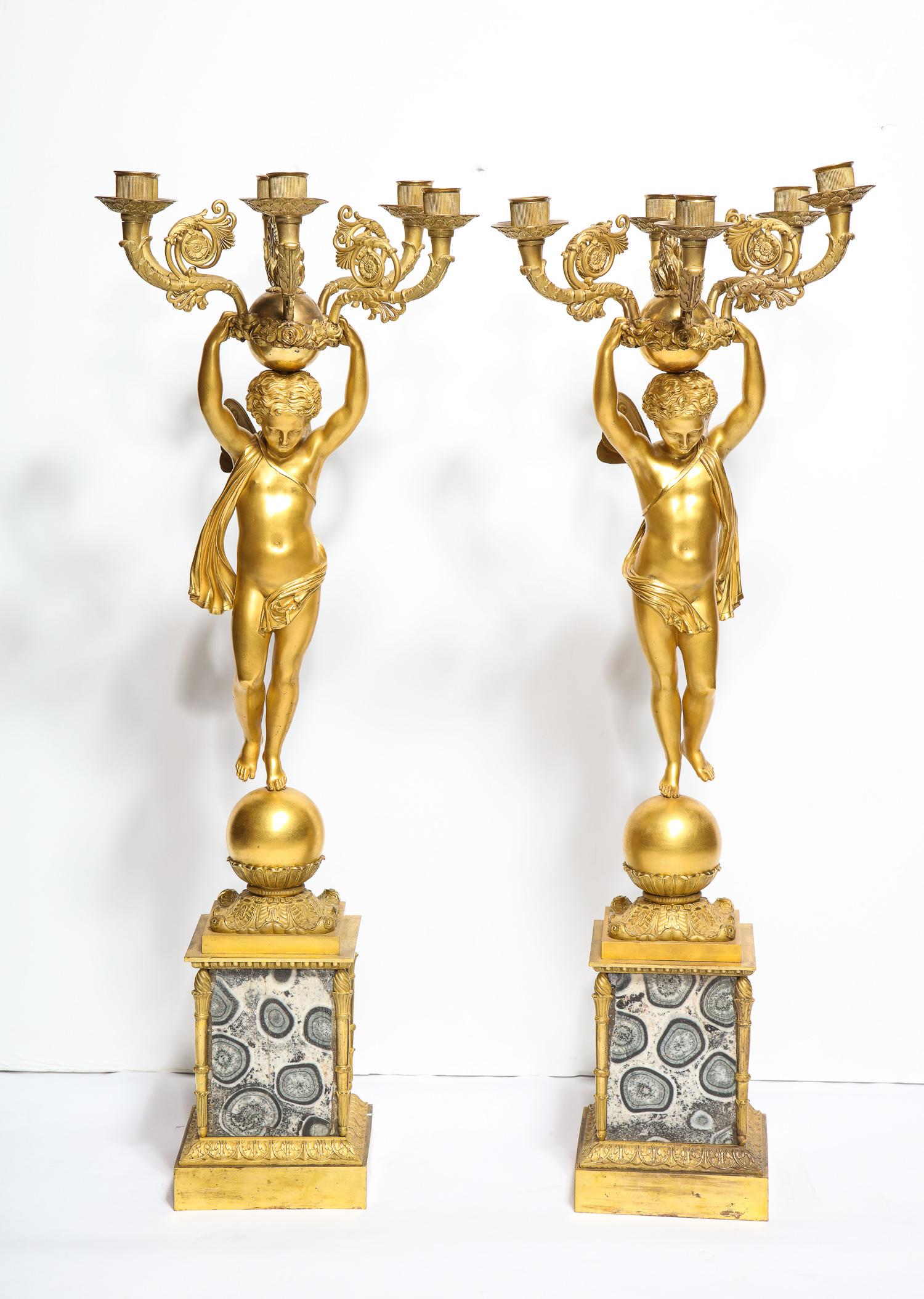 Large pair of French Empire ormolu bronze candelabra on granito (granite) orbicolare bases, circa 1820.

Exquisite quality ormolu candelabra on very rare original granite bases.

The winged figures depicting two cherubs, each holding the