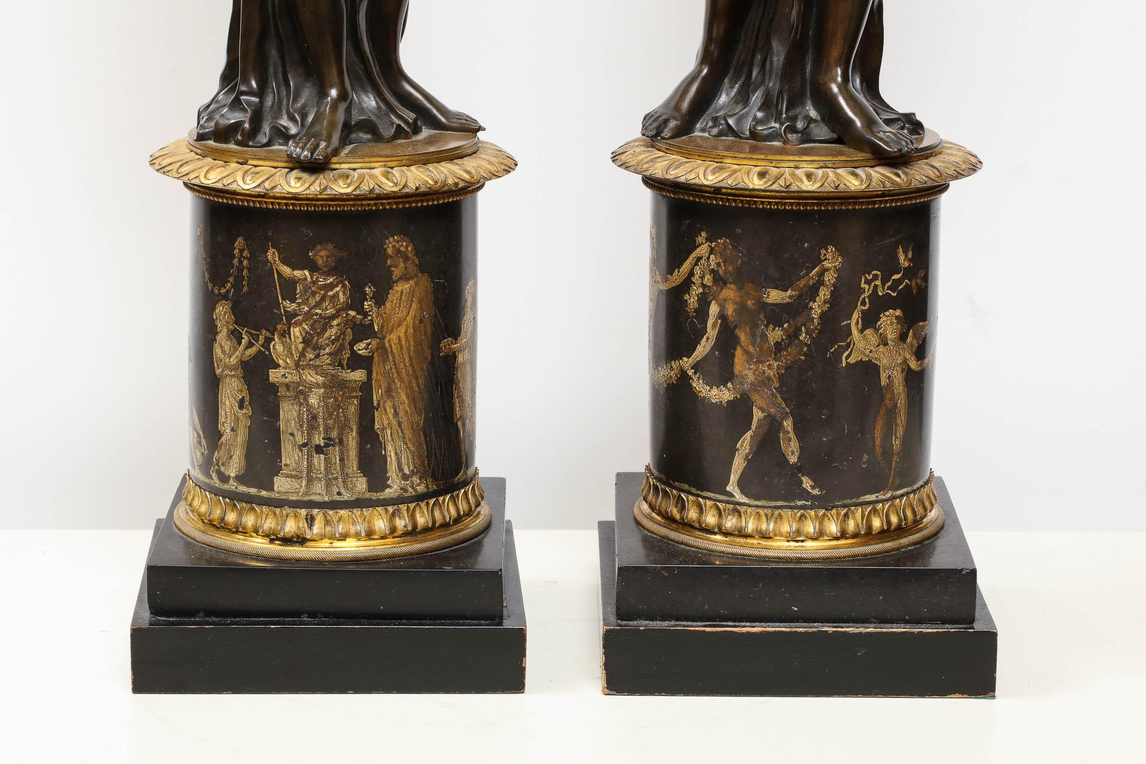 Large pair of French gilt and patinated bronze figural candleholders,

circa 1820-1830. 

In the manner of Francois Remond, each modeled as a maiden holding a cornucopia above a cylindrical pedestal painted to show a continuous band of classical