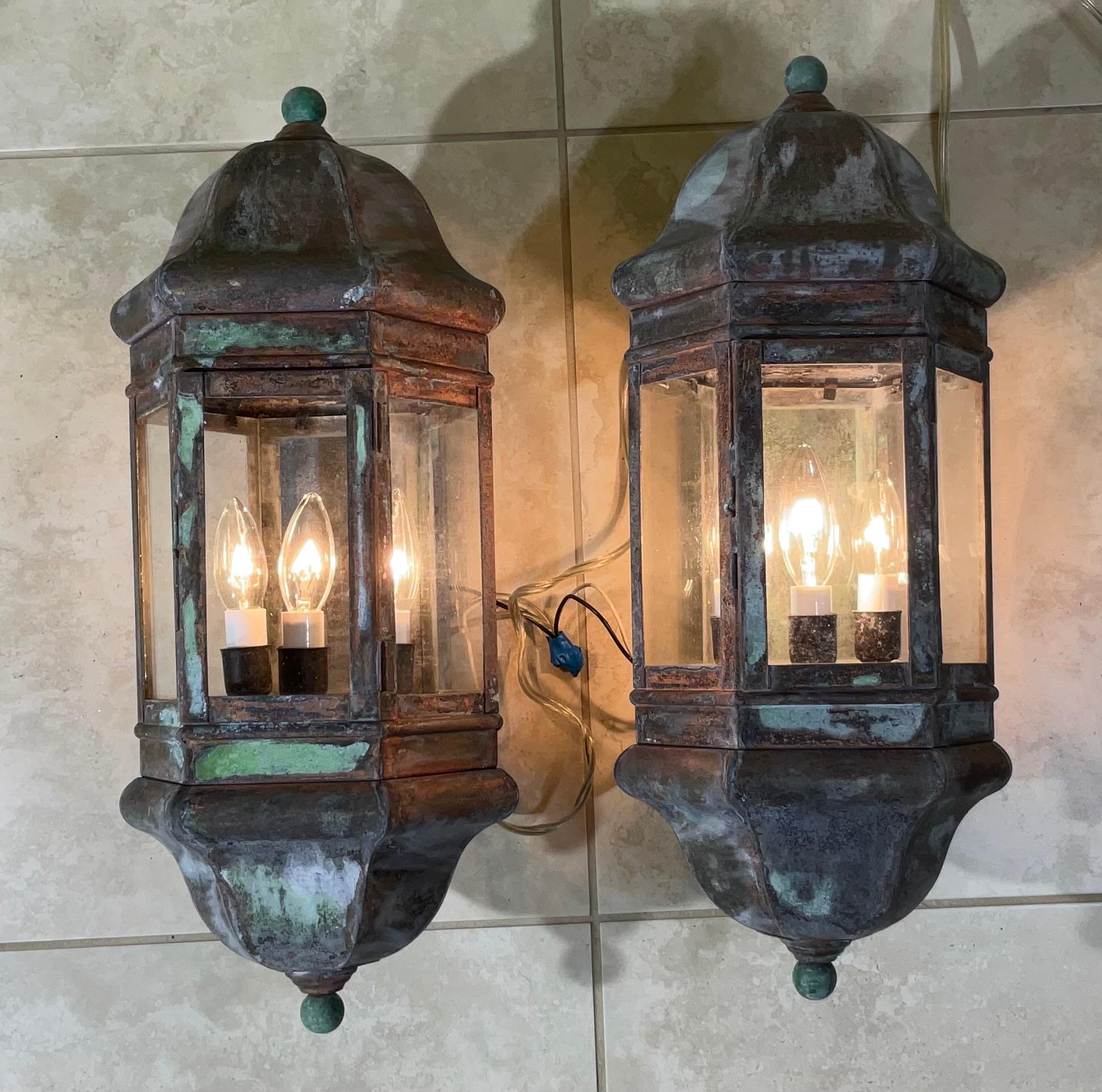 Hochwertiges Paar Wandlaternen, handgefertigt aus massivem Messing mit drei 40-Watt-Lampen pro Laterne, geeignet für Feuchträume. 
Schöne oxidierte Patina.