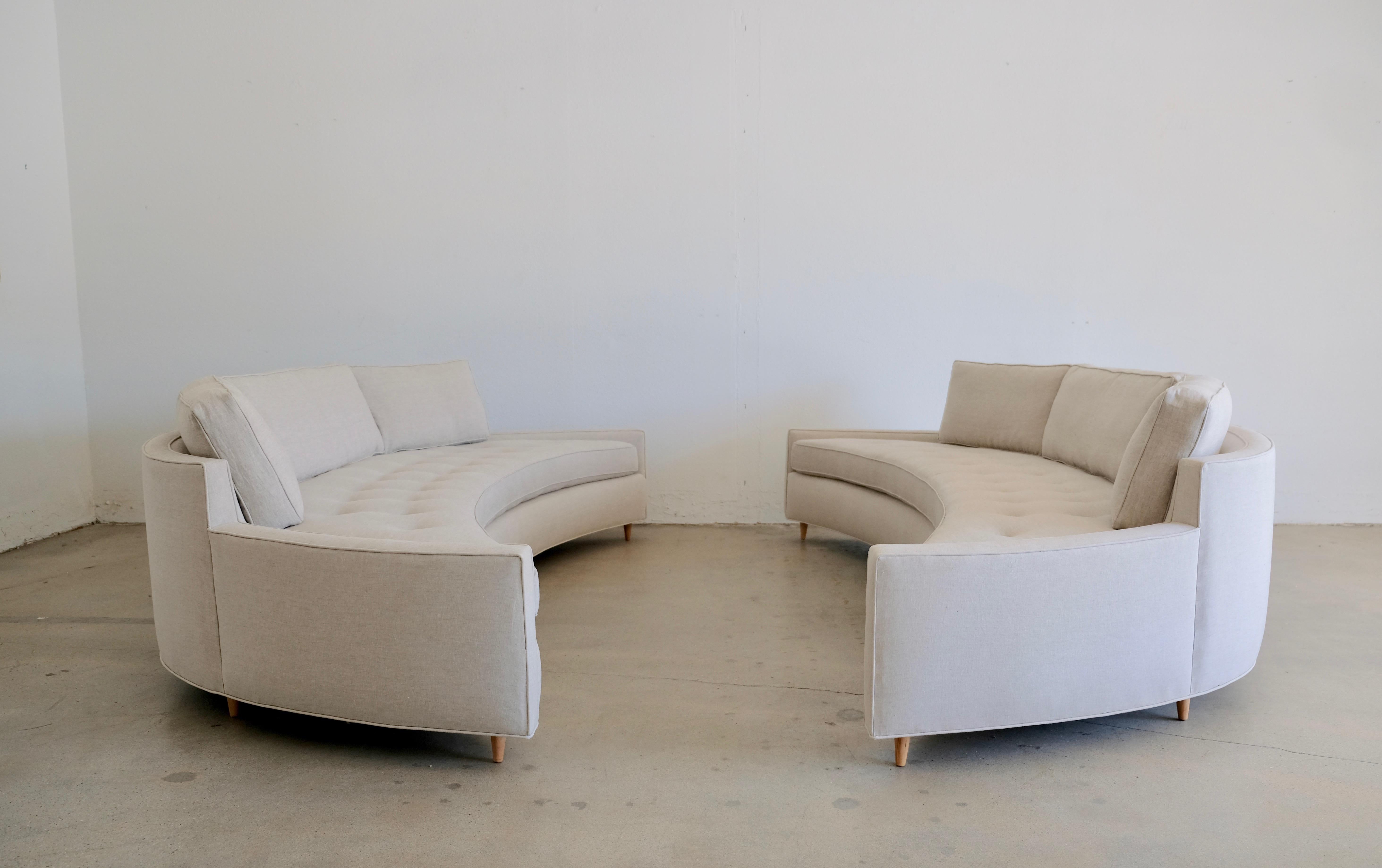 A massive matching pair of curved restored attributed to Harvey Probber curved sofas. The tufted curved seat foam has been replaced. The back cushions are down filled. The restored cone legs are Japanese maple. The fabric is a natural light stone