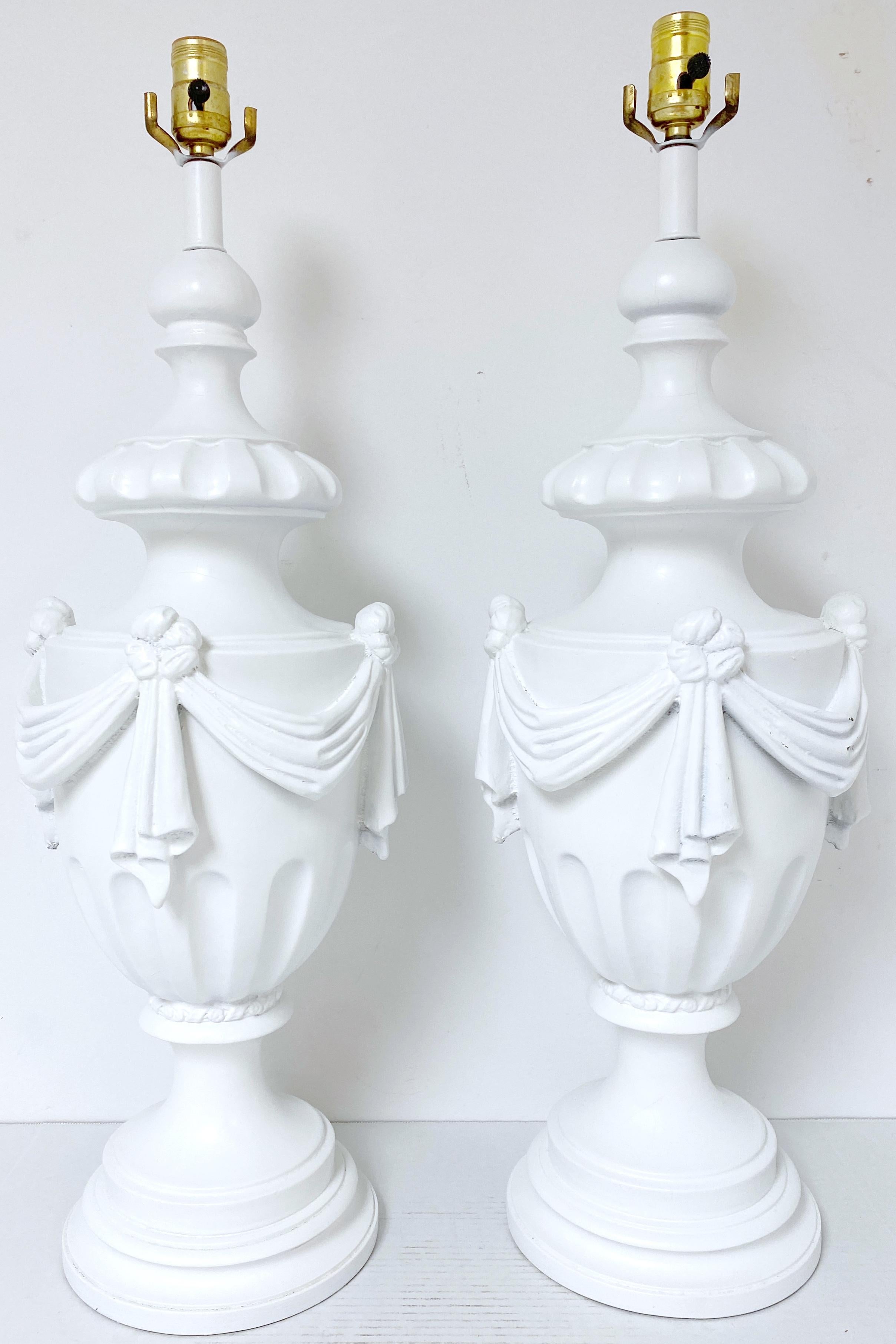 Large Pair of Hollywood Regency Neoclassical White Lacquered Draped Urn Lamps 
USA, Circa 1950s

Add a touch of quiet glamour to  your living space with a touch of elegance through this exquisite pair of Large , Pair of Hollywood Regency