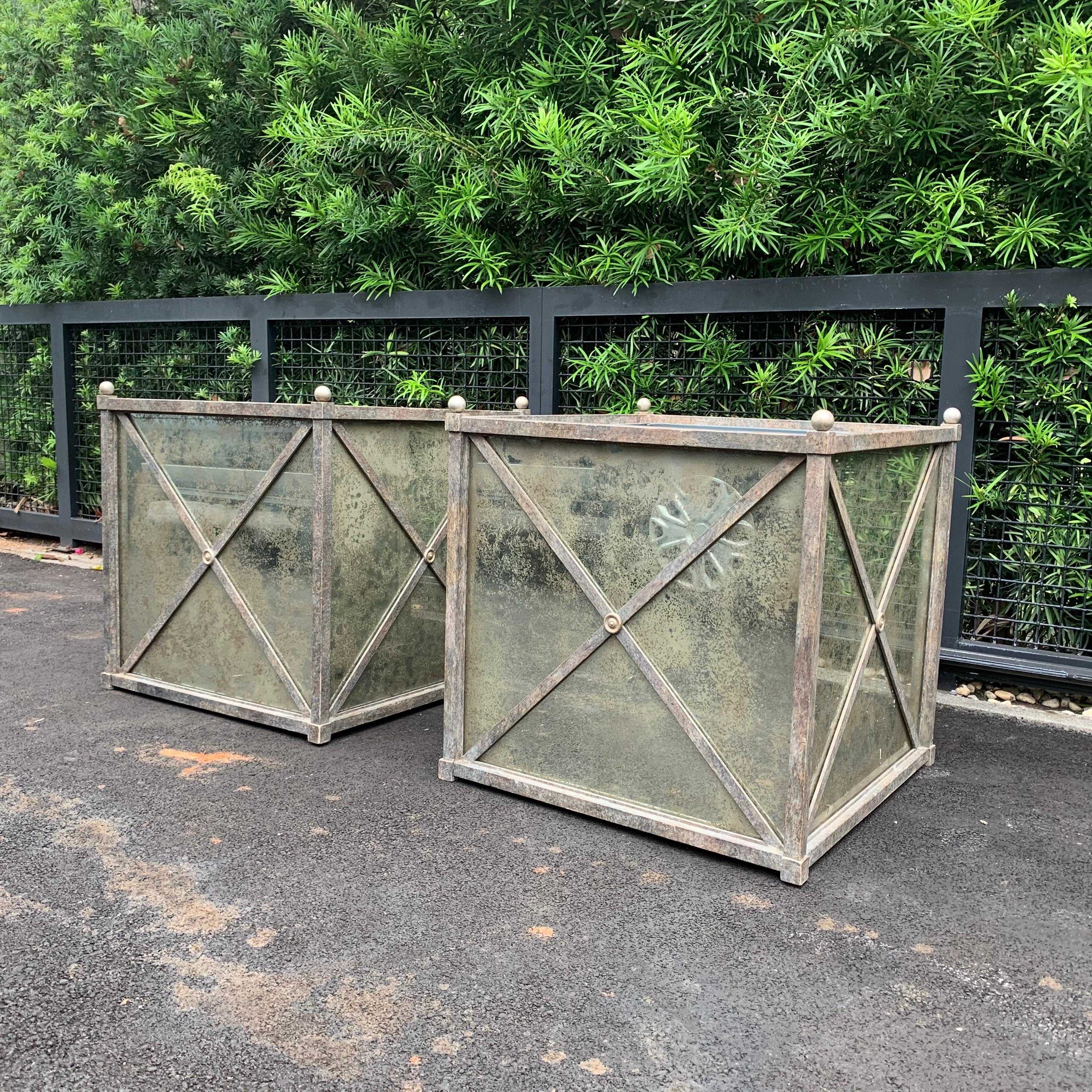 These palatial oversized Hollywood Regency style heavy iron and gilt brass detail planters with antiqued mirror panels. Galvanized liner. Sold as pair only.