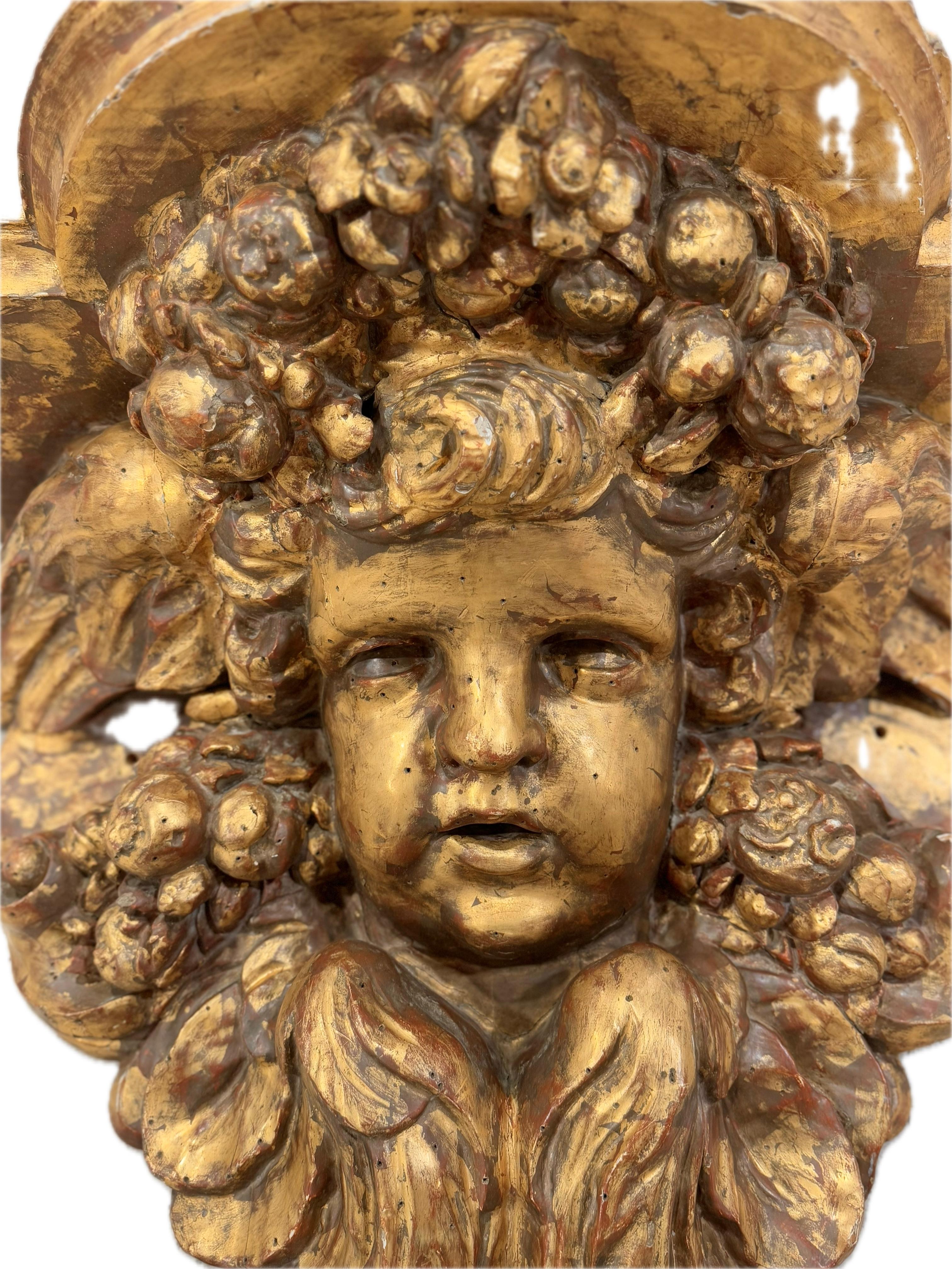 Très grande et étonnante paire de consoles murales baroques en bois sculpté et feuilles d'or du début du XVIIIe siècle. Les visages d'angelots de la paire sont entourés d'ailes, de fruits et de fleurs sous des surfaces supérieures plates et