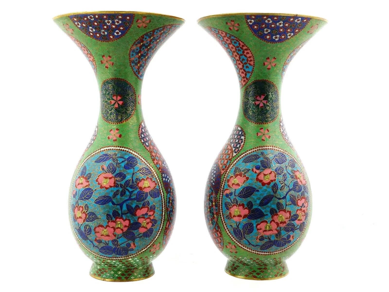 A pair of identical Japanese enamel over copper vases. Each vase has a globular shaped body and a wide neck with a fluted mouth. Each vase is enameled with a polychrome design representing medallions with blossoming flowers and sakura trees