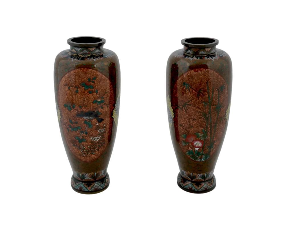 A pair of Japanese enamel over copper vases. Each vase has an urn shaped body and a wide neck. Each ware is enameled with polychrome medallions depicting a bird seated on a branch, blossoming flowers, and bamboo trees surrounded by circular floral,