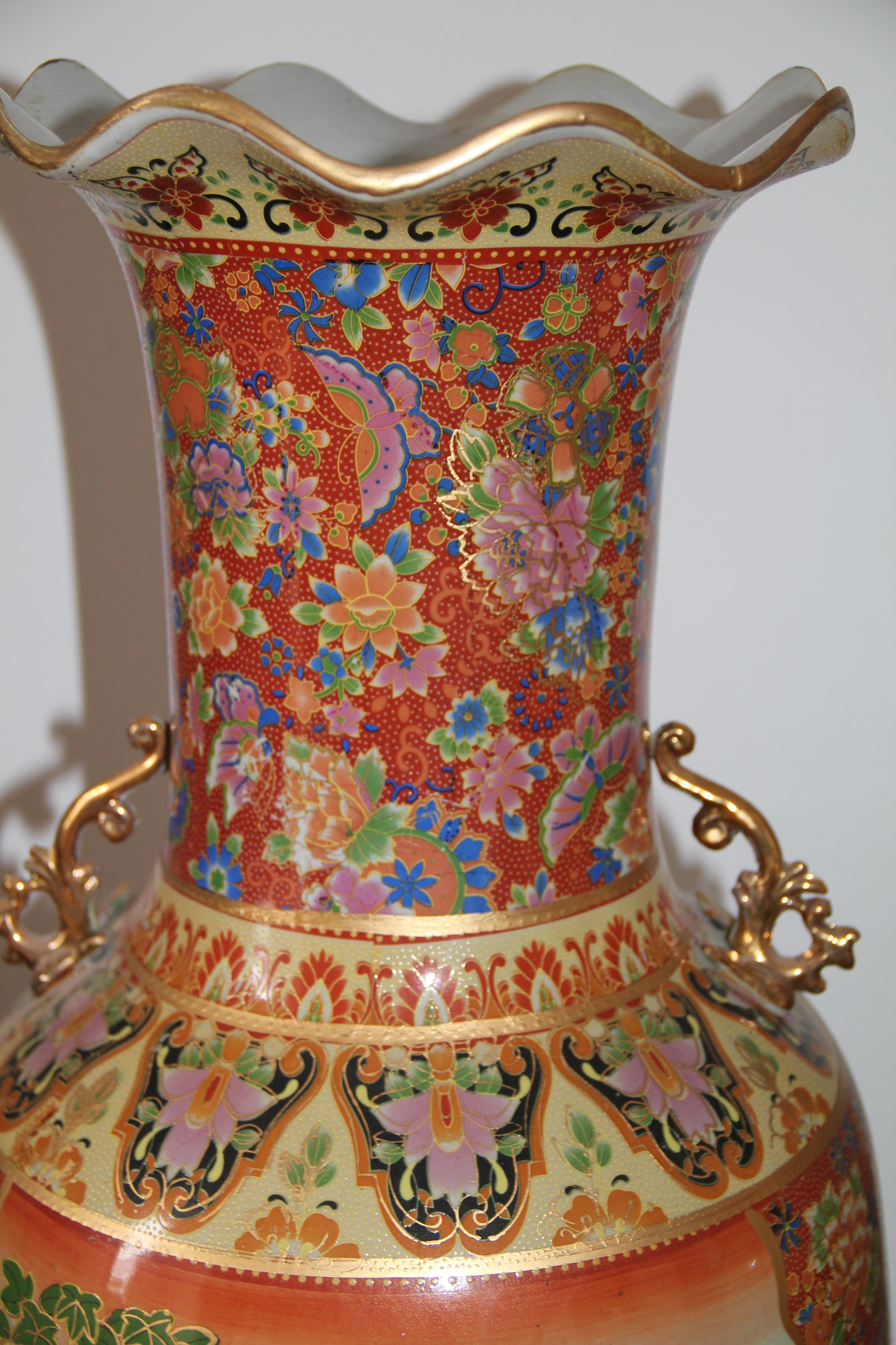 Large Japanese Vases in Chinese style, decorated in hot colors with large panels, ladies in a flower garden and an equestrian procession in a coastal landscape, and otherwise with flowers and foliage, the handles as gilt scrolls, a red bat symbol