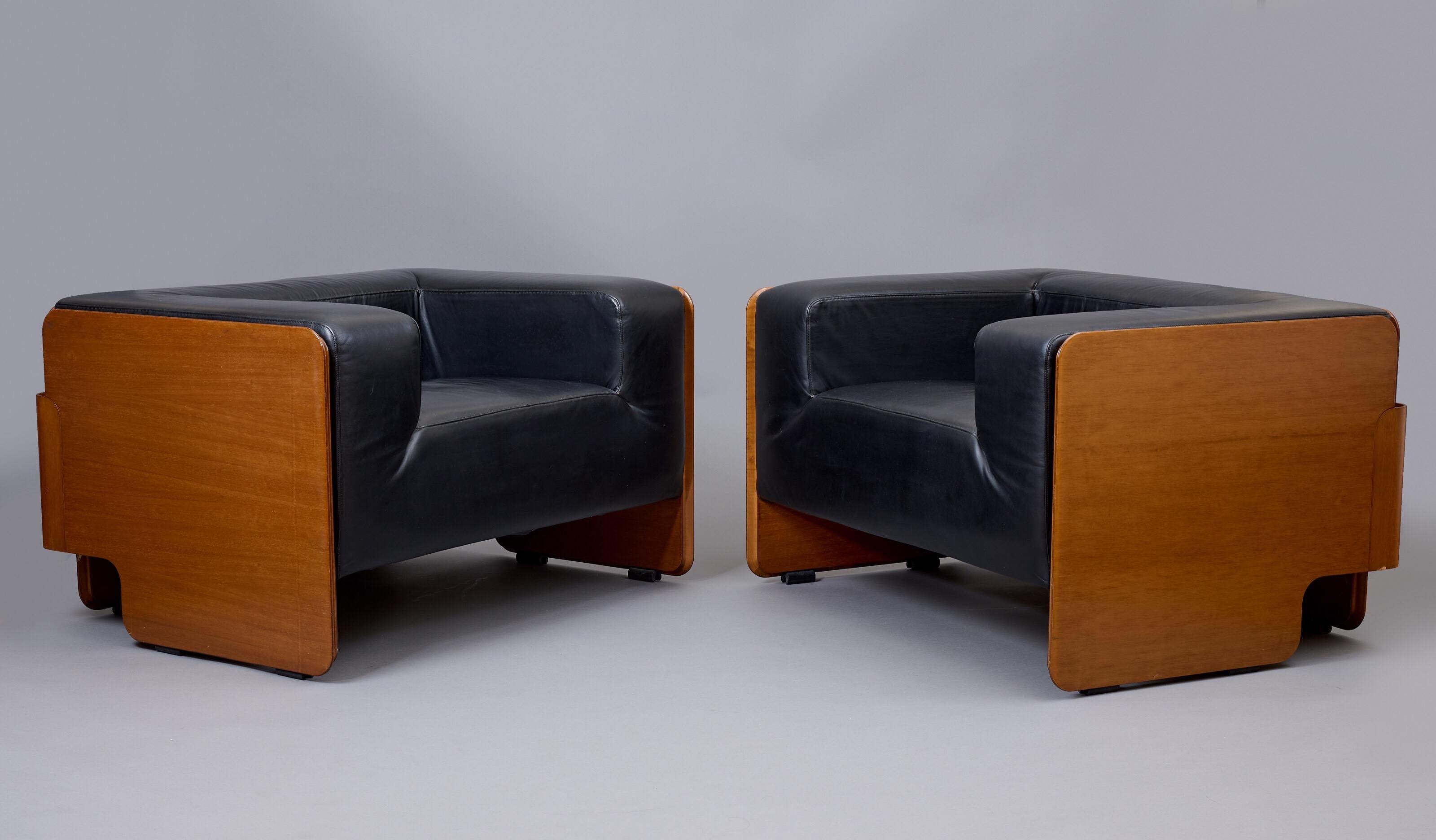 Italy, 1970s

A massive, voluptuously comfortable pair of geometric club chairs in walnut and black leather. A three-paneled rectangular armature in walnut veneer, with rounded edges and fluid cut-outs along the sides and back, wraps around a deep,