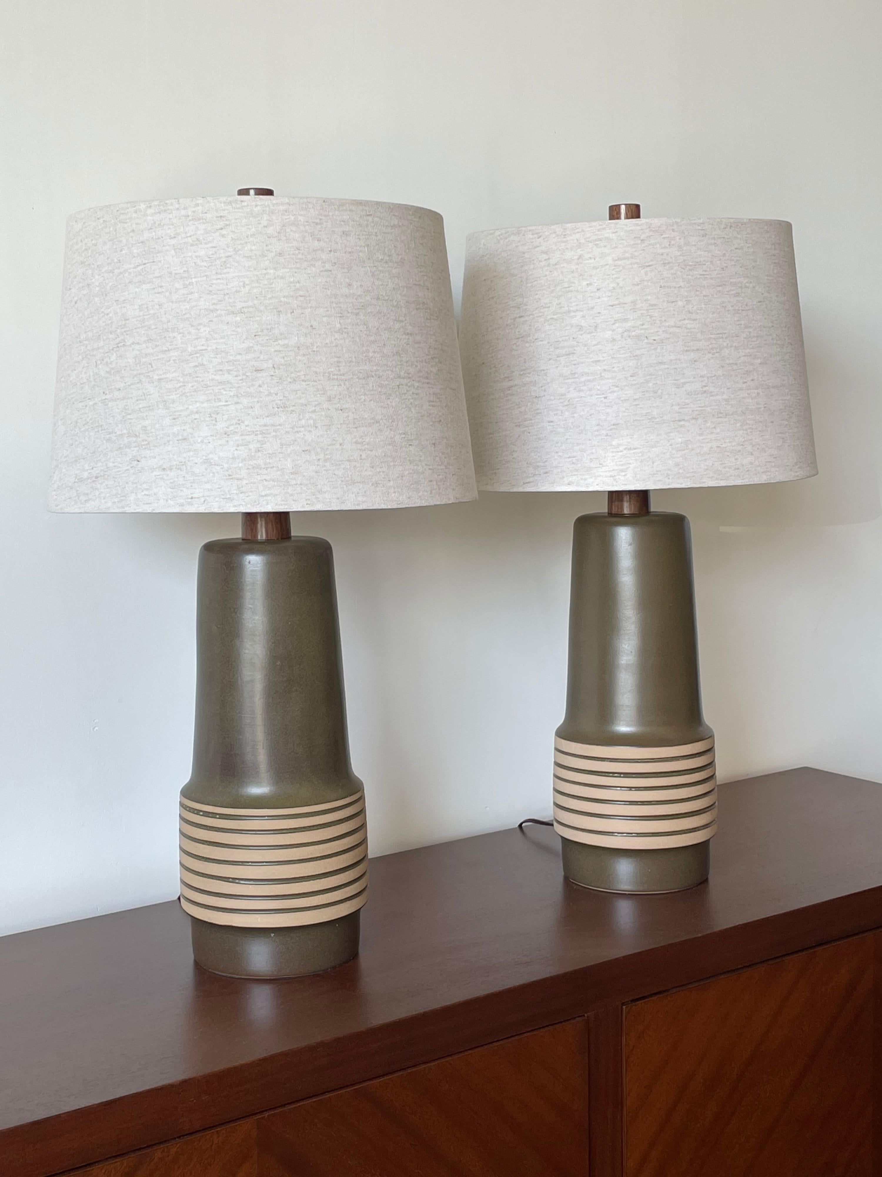 A wonderful pair of large ceramic lamps by ceramicist duo Jane and Gordon Martz for Marshall Studios. A predominately dark green color with slight hues of a plum underneath. These lamps were sourced as “new old stock” ceramic lamp bases. They are