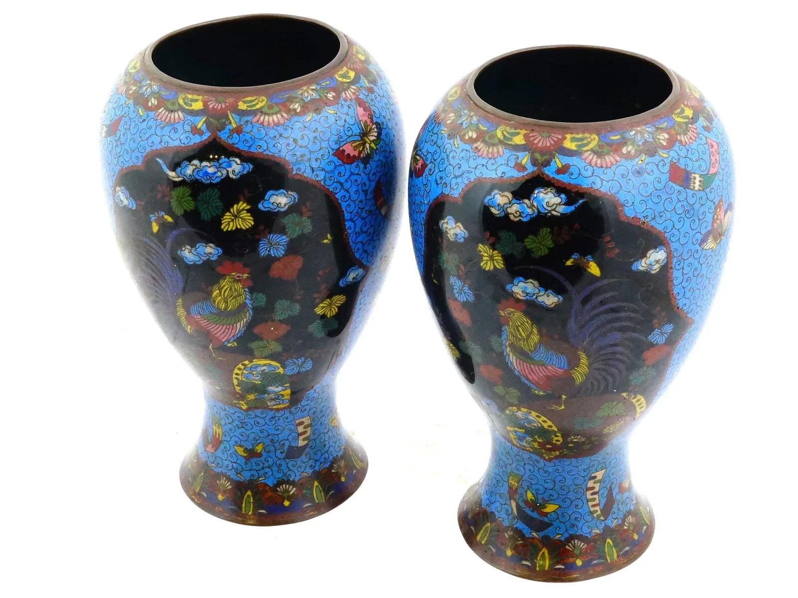Un par de jarrones japoneses idénticos de esmalte sobre cobre. Cada jarrón tiene un cuerpo de forma globular y un cuello ancho. Cada jarrón está esmaltado con un diseño policromado que representa medallones con un gallo rodeado de hojas y nubes y