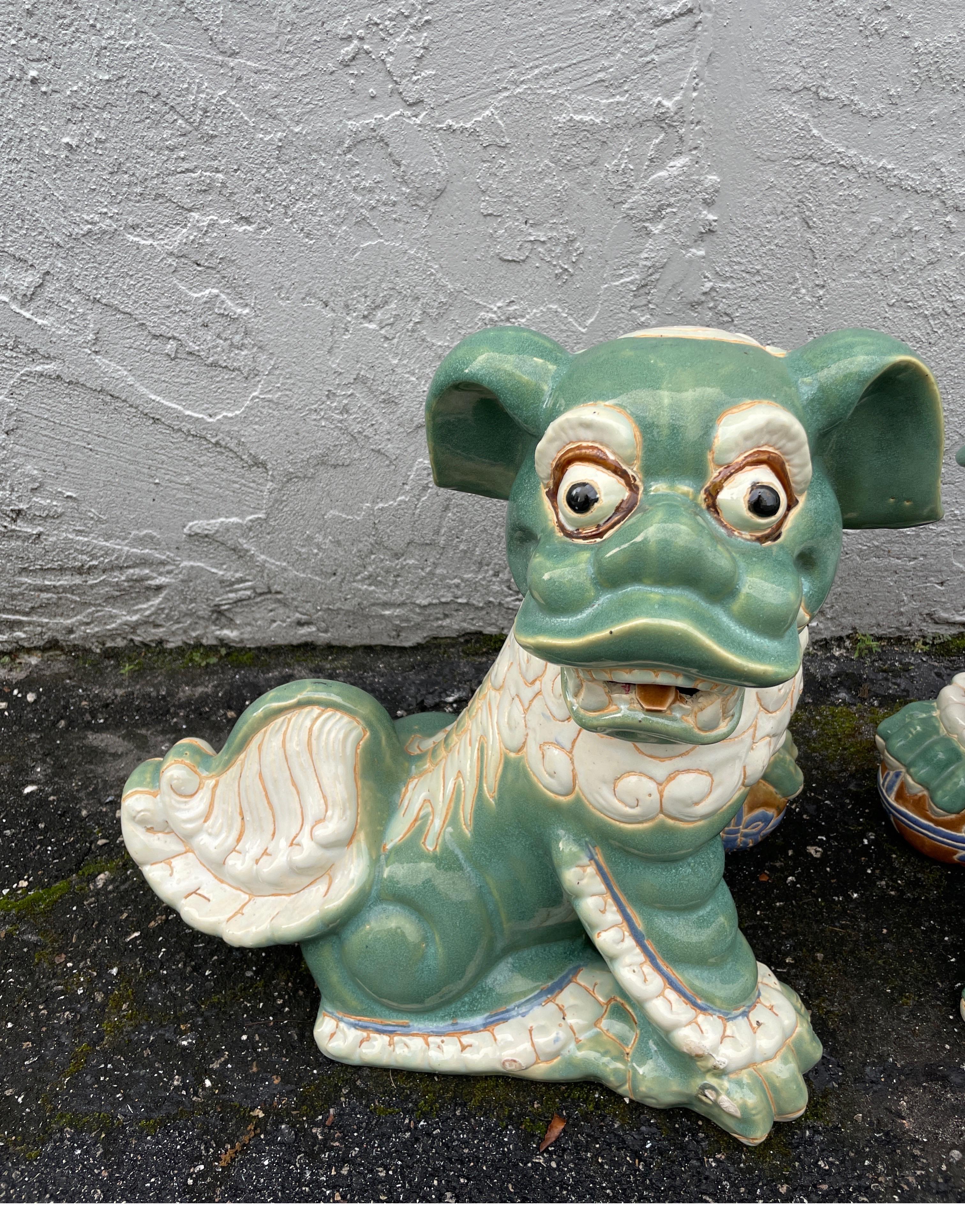 Unique pair of large mid-century Chinese Foo Dogs in a shade of green and cream.
