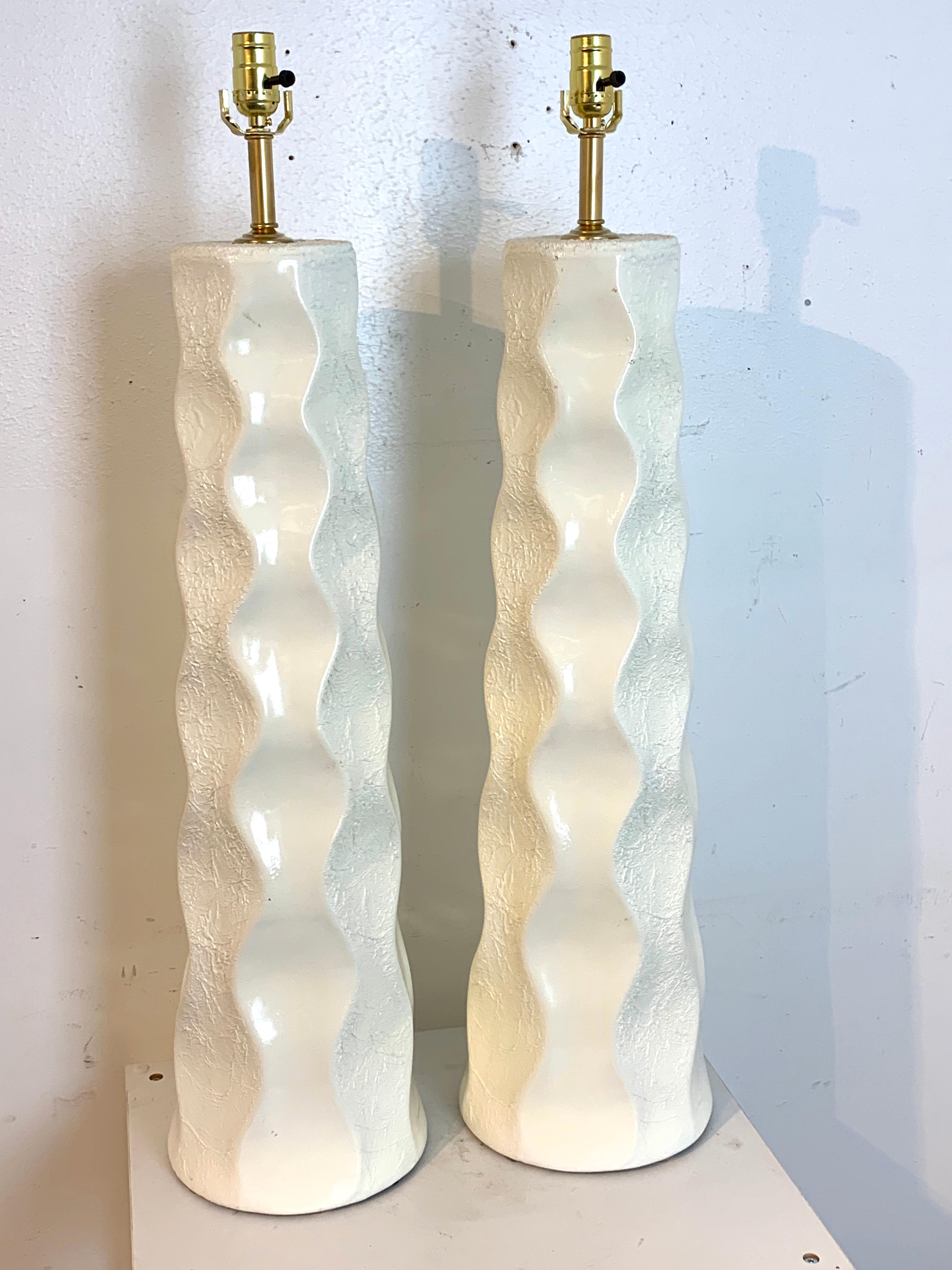 Large pair of Mid-Century Modern undulating textured column lamps, in white, each one a sculpture with alternating undulating lines.
Each lamp stands 31
