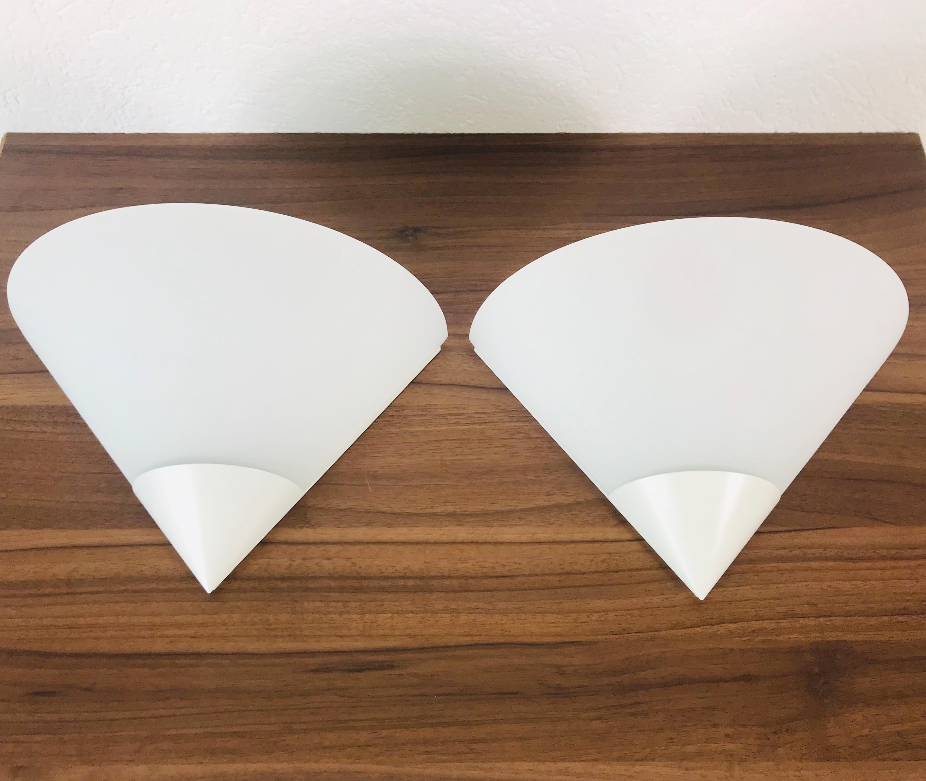 A beautiful pair of Mid-Century Modern wall lamps by Glashütte Limburg made in Germany in the 1970s. It has a beautiful triangle shape and is made of aluminium and opaline glass. The back is white metal.

The light requires one E27 light bulb.