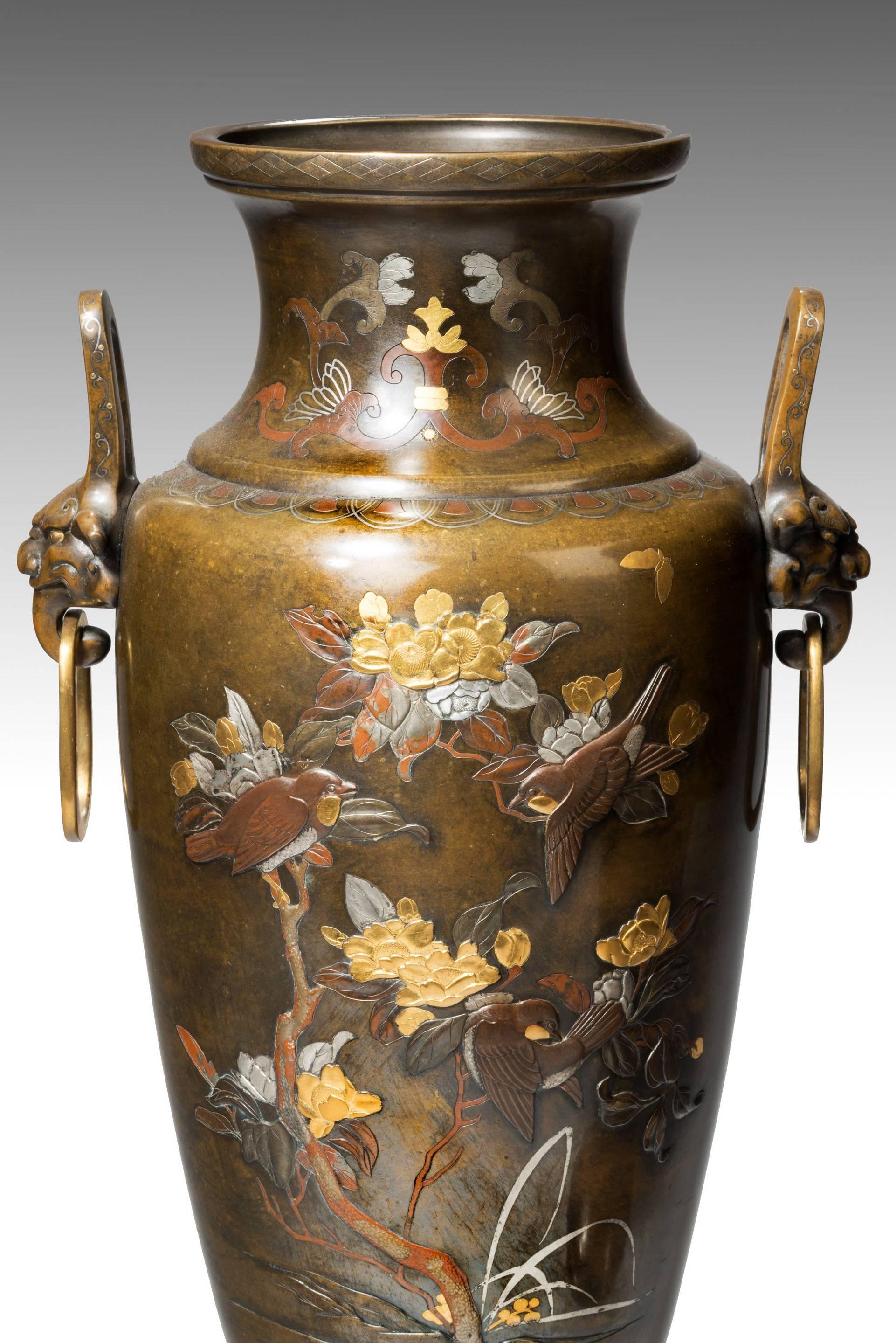 A large pair of mixed metal Meiji Period vases, 

Each of baluster form, with ring and mask handles, decorated throughout with silver gold and shakudo inlays with birds flying amongst flowering plants.