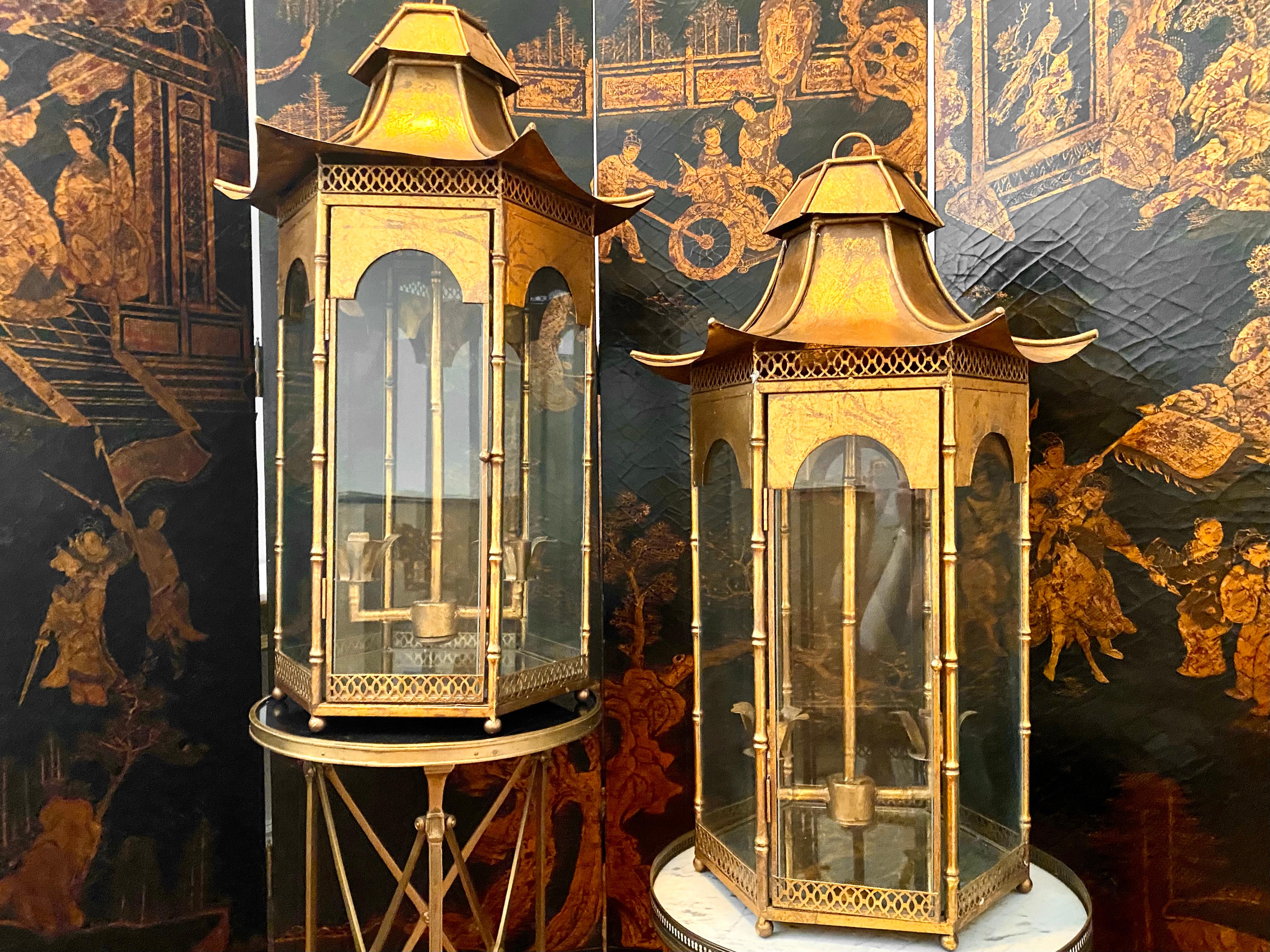Large pair of Pagoda Chinoiserie gilt bronze lanterns, Mid-Century Modern.
Exceptionally decorative and beautiful, each lantern has a pair of candle holders accessible through a hinged glass door. The pagoda shape is accentuated from the curve of