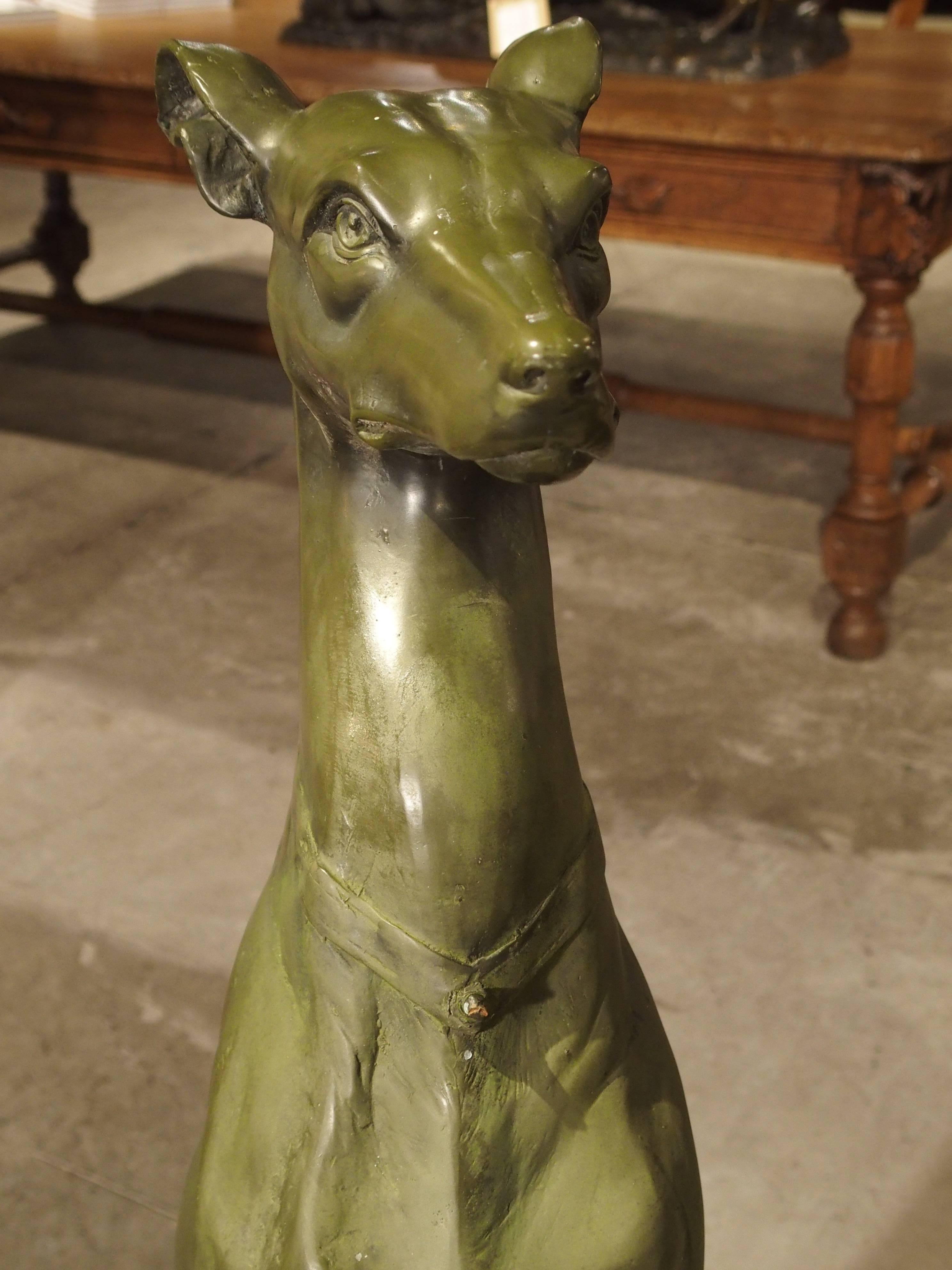These wonderful metal dogs are seated on stands of round stone, and they are after the French sculptor, Antoine Barye. They are a light green in color, mimicking bronze. Each dog (likely Whippets), rest upon octagonal pedestals with foliate motifs.