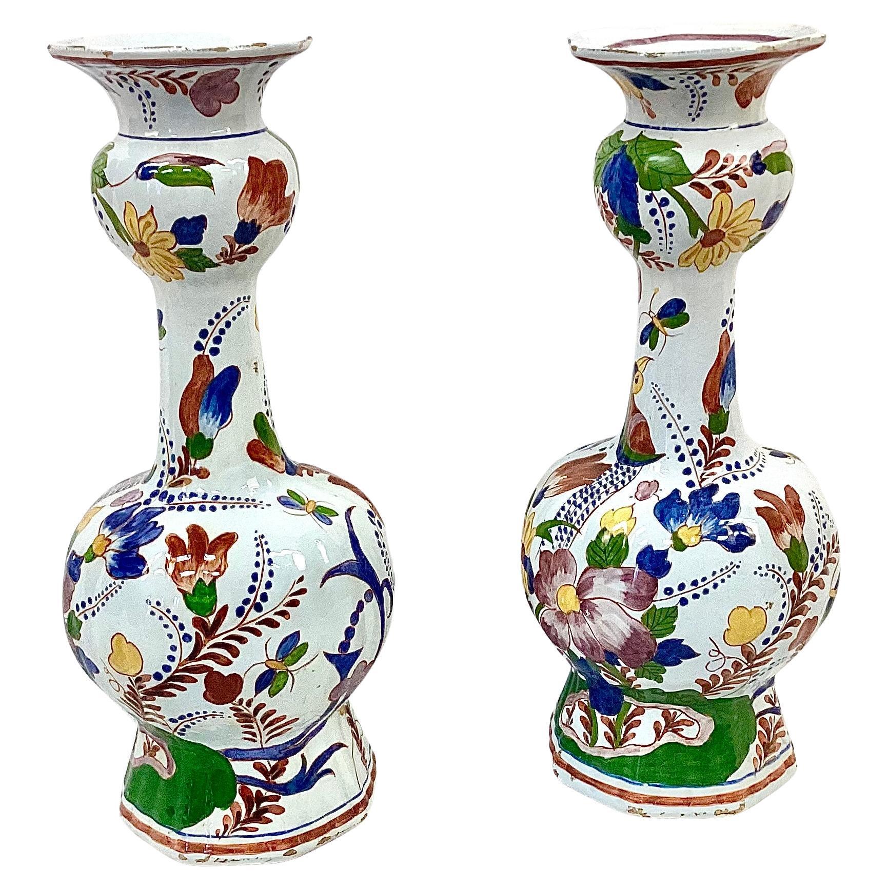 Large pair of hand painted Dutch Delft vases. Painted on the vases are birds, butterflies and florals in vivid colors of cobalt blue, green, yellow and pink on a white background. The mark of Wemmersz Hoppesteyn on the bottom