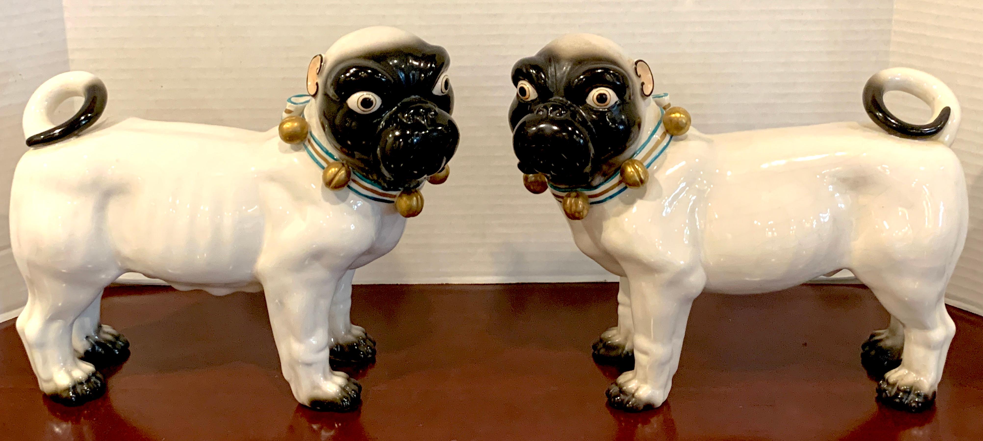 Large pair of porcelain standing pug dogs with bell collars, realistically modeled, well painted, a true pair one facing left, one facing right. Signed 'Italy with painters marks'.