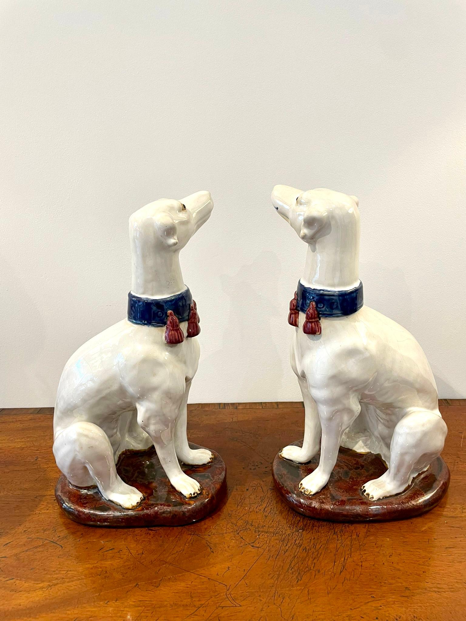 Large pair of quality antique Victorian continental greyhounds of fantastic quality seated greyhounds with blue and red collars on an oval red/brown coloured base.

In perfect original condition.

Measures: 35 x 15.5 x 22cm
Date 1880.
 