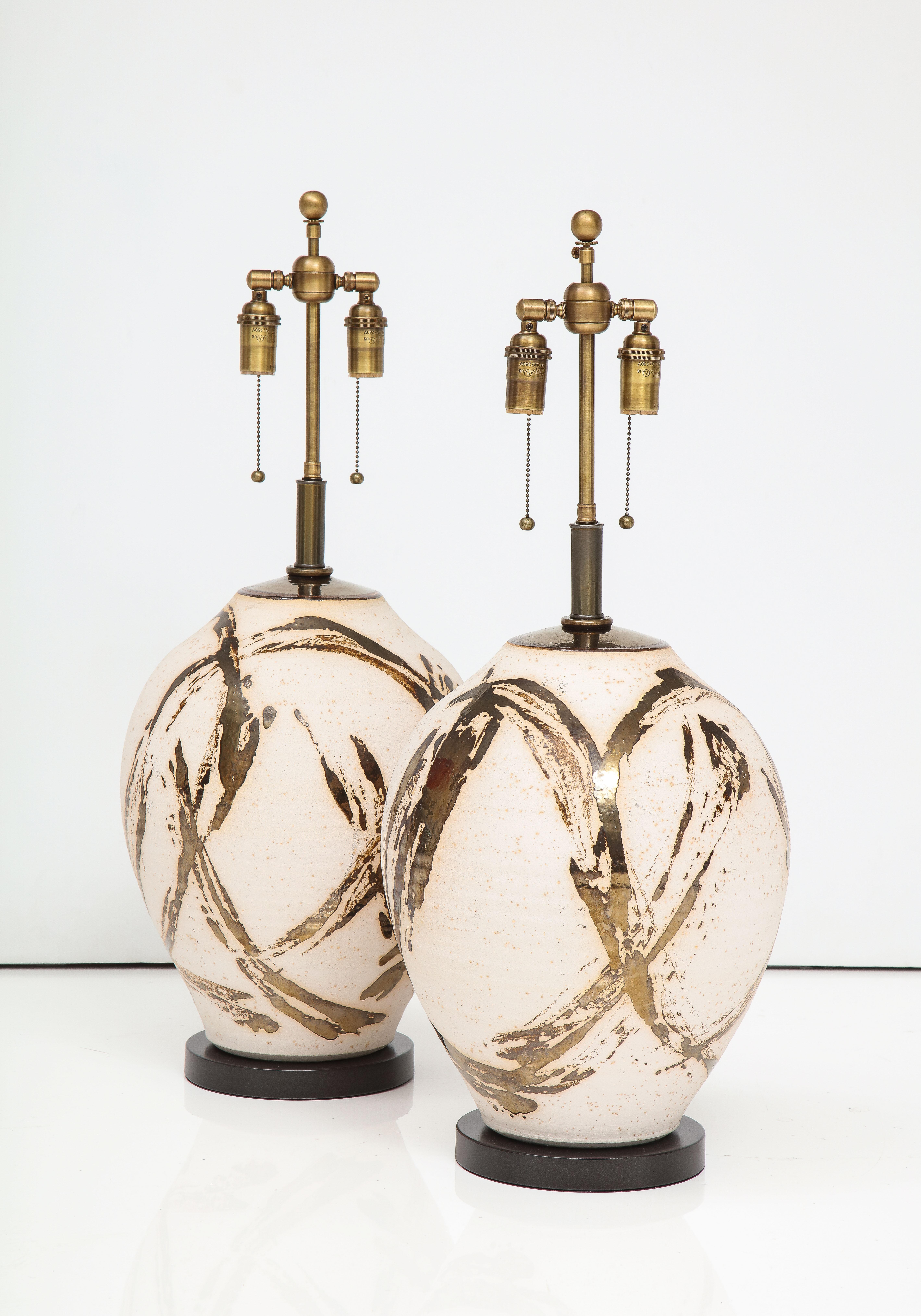 Großes Paar Raku Ware-Lampen, entworfen für eine Einrichtung von Steve Chase.
Die Lampen haben eine wunderbare Batik-Stil Metallic glasierte Oberfläche, und sie haben
wurde neu verkabelt mit verstellbaren Doppelclustern aus antiker Bronze und