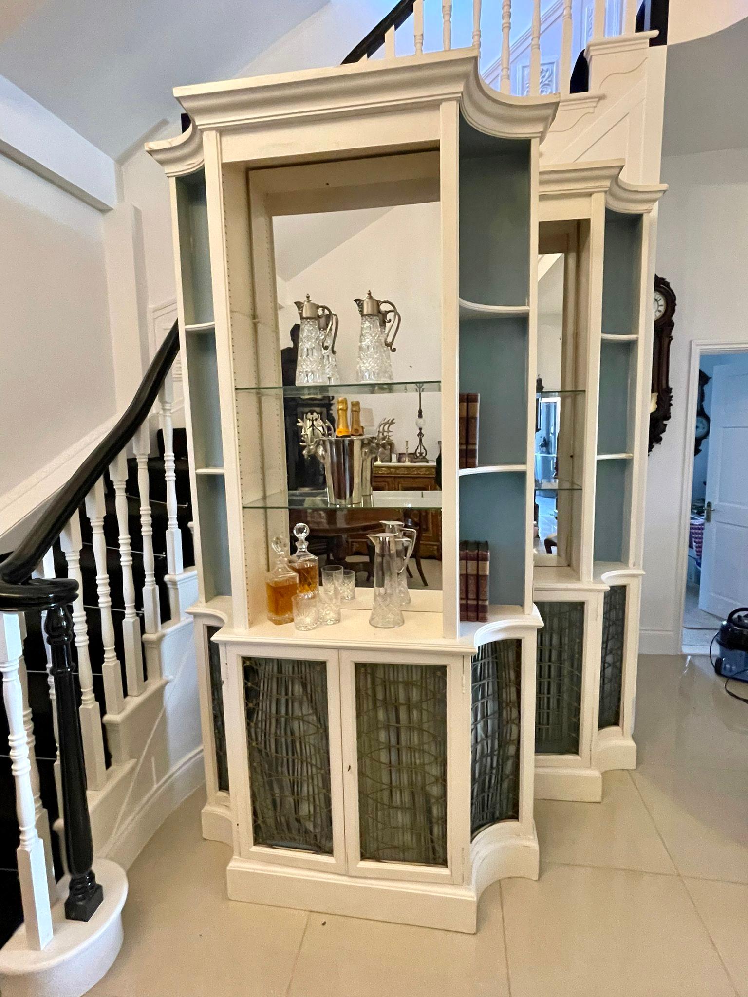 Large pair of regency style quality breakfront bookcases having a pair of white painted regency style open top breakfront bookcases above a pair of brass grille cabinets

H 247 x W 126 x D 40cm
Date 1940
