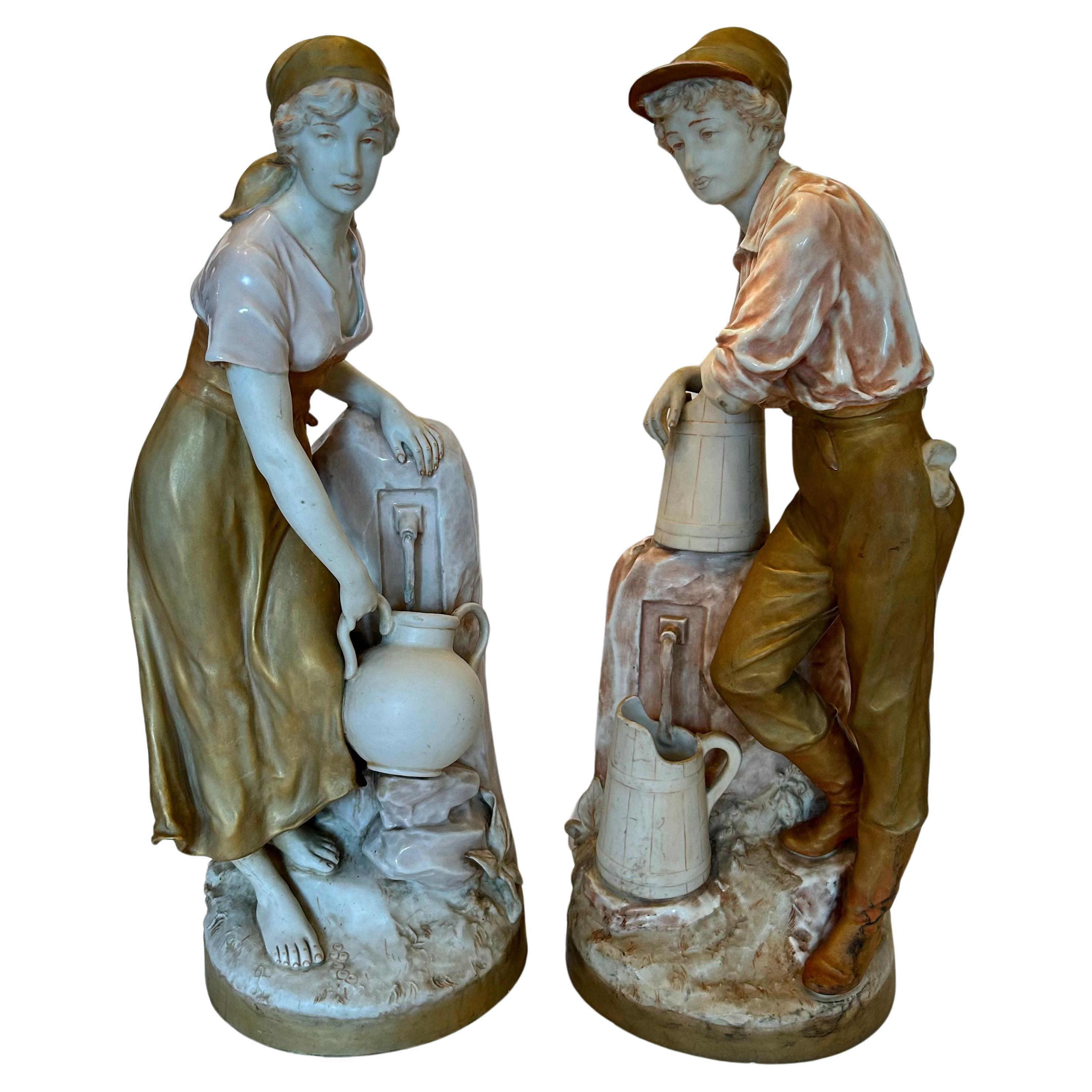 A beautiful pair of monumental biscuit porcelain figures made by renowned Royal Dux Bohemia, depicting a girl and boy, each one at a well. 
Stamped with the pink, triangular Royal Dux Bohemia E mark under the base.
Lovely porcelain biscuit