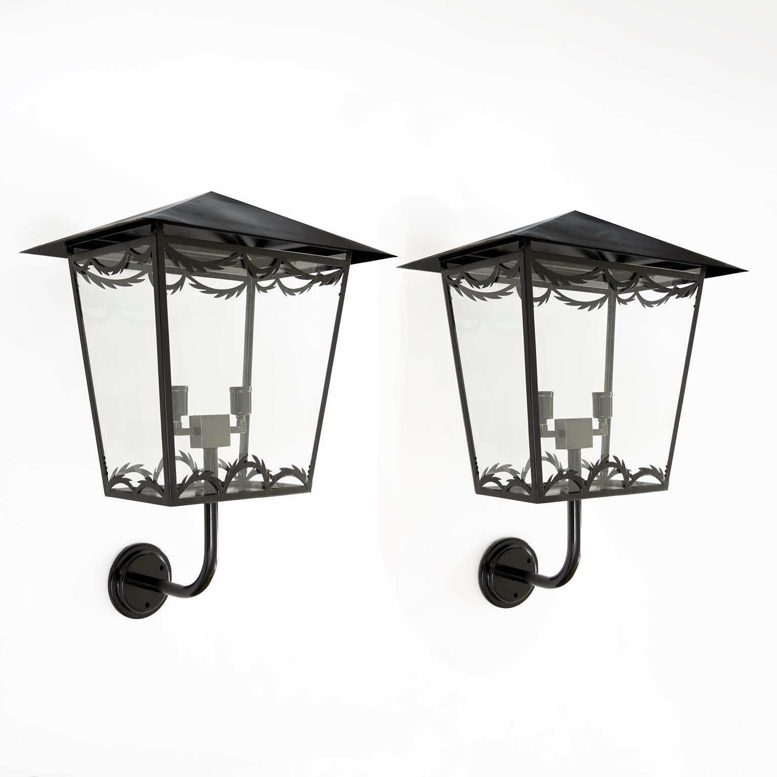 A large pair of Scandinavian midcentury wall-mounted lanterns with glass sides. Each wall lantern has been newly painted and wired with custom patinated brass cluster with double standard base porcelain sockets for use in the USA. The peaked roof