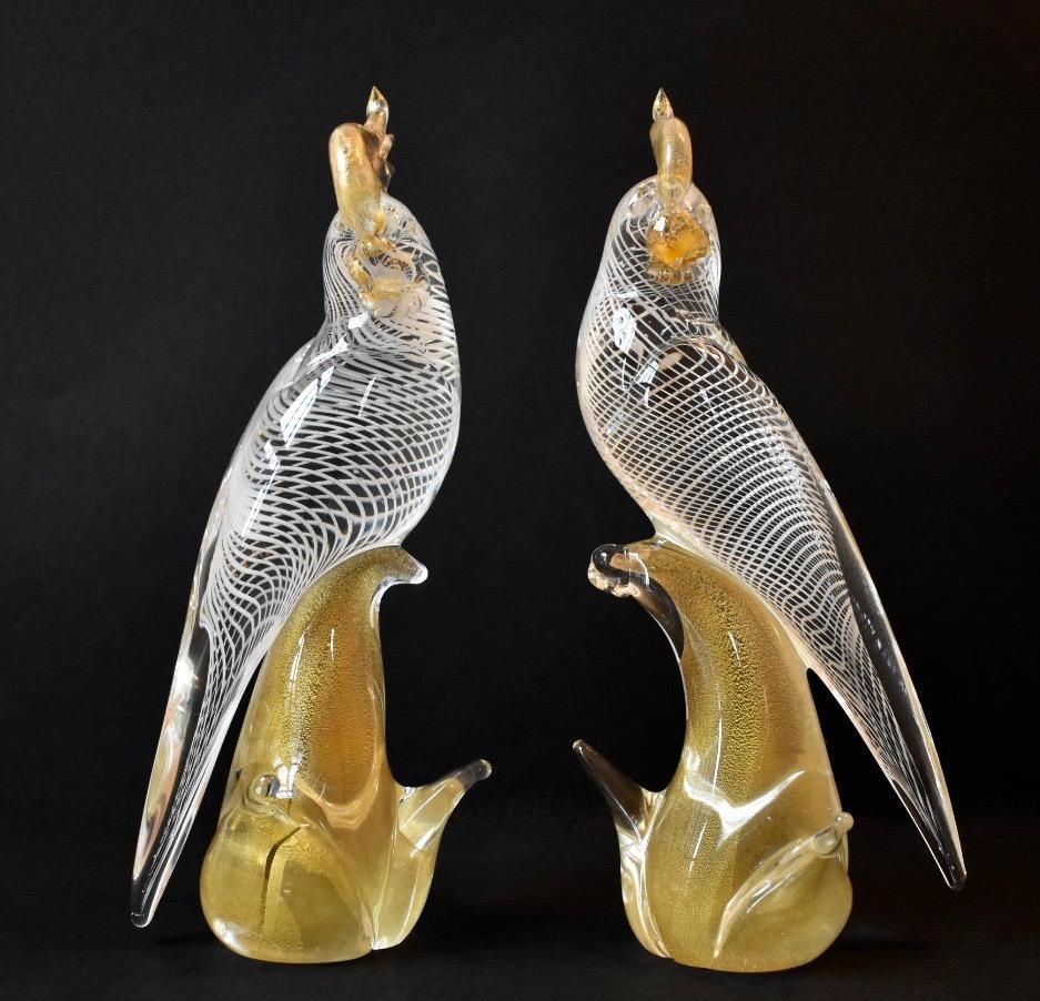 A large pair of Murano glass cockatoo sculptures by Archimede Seguso. Each bird rests atop a gold infused clear glass base. The clear glass body of each bird has delicate white glass swirls that move upwards towards gold infused eyes, beak and