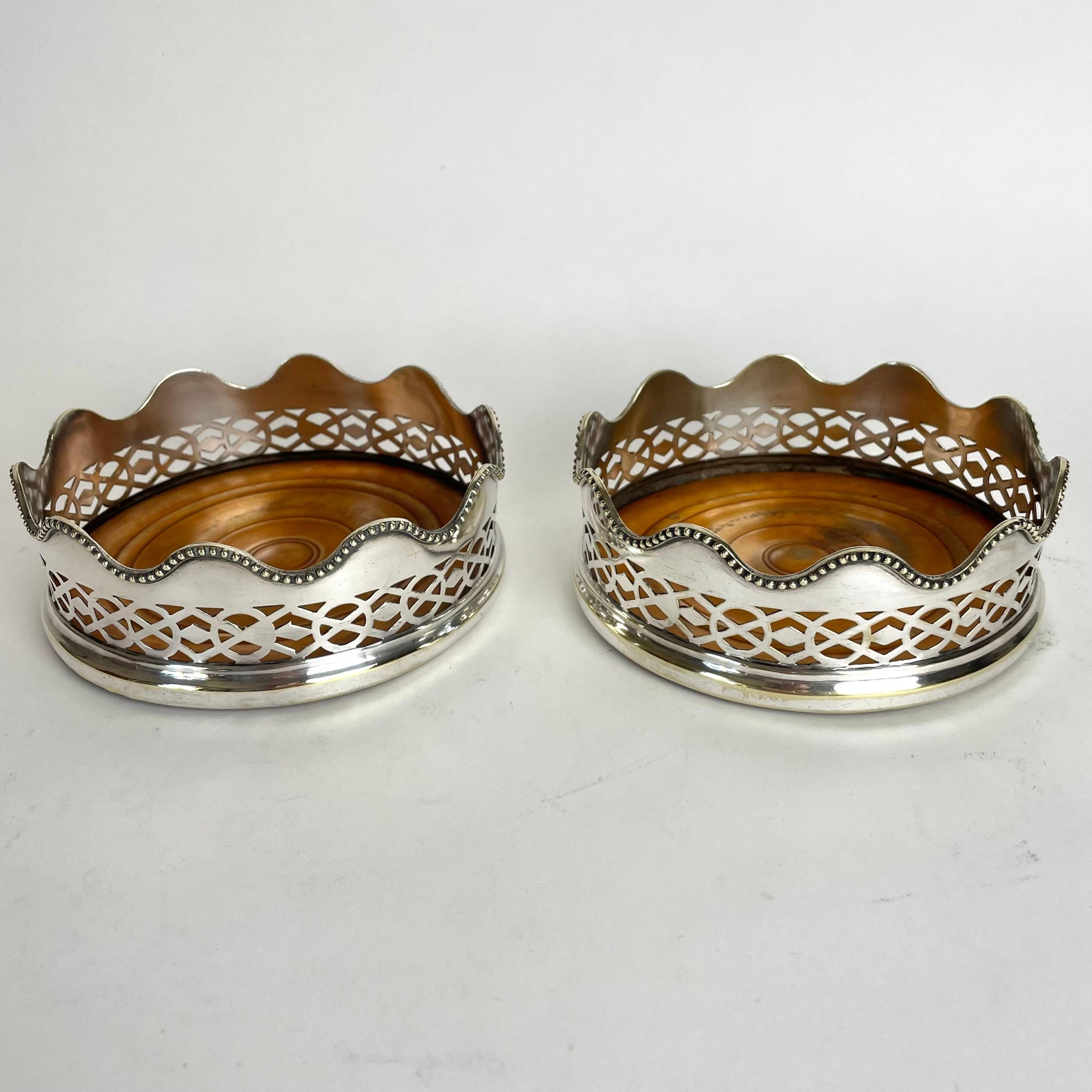 Une élégante paire de sous-verres à champagne en métal argenté du début du 20e siècle avec des bases en bois.

Usure correspondant à l'âge et à l'usage. 