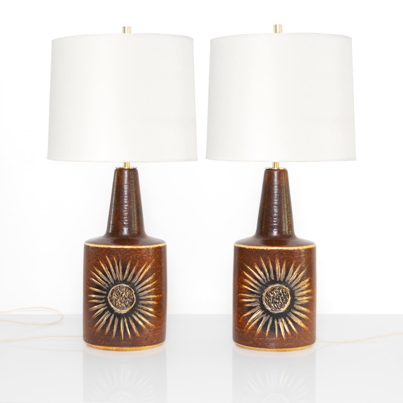 Large pair of Scandinavian modern ceramic lamps with incised flower motif on the front and reverse. Made by Soholm on the island of Bornholm, Denmark. Newly rewired with polished brass hardware, double socket clusters for use in the USA. 
Shades