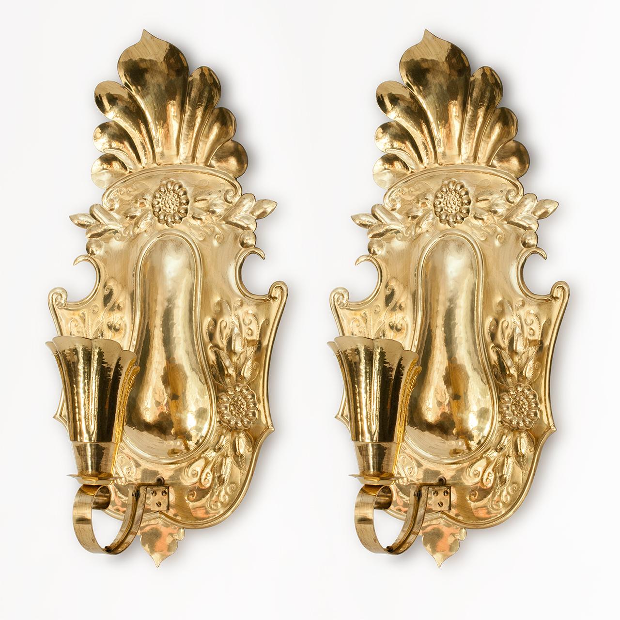 Grande coppia di applique svedesi in ottone martellato dell'inizio del XX secolo. Ispirate al barocco svedese, le applique hanno paralumi a forma di conchiglia stilizzata che ospitano prese di corrente a base standard. Misure: Altezza 25,5
