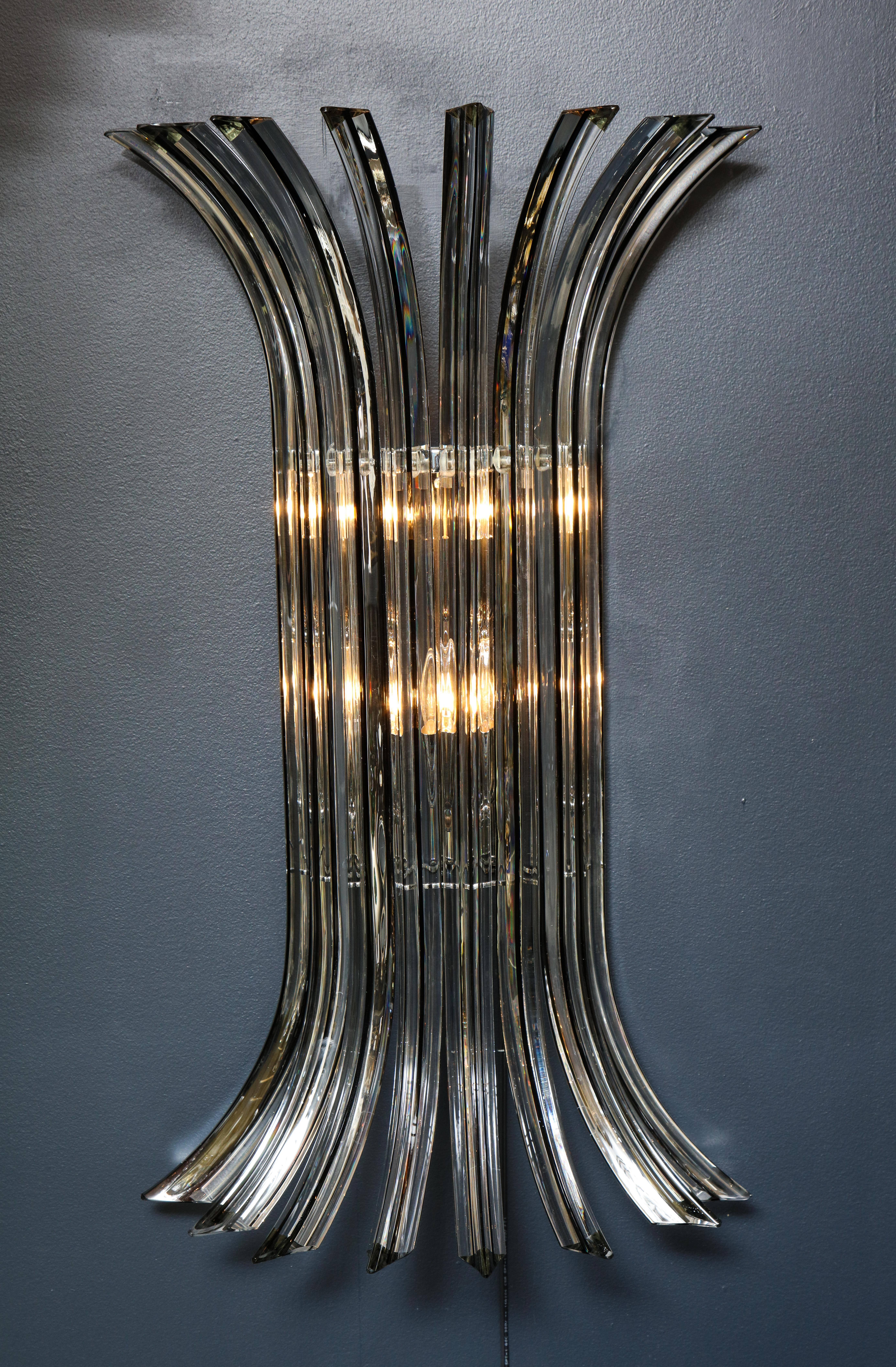 Large pair of Italian hand blown Murano glass sconces made of eight curved rods in clear Murano glass with a fine black glass core or vein in the center. The light bounces beautifully off the “Triedi” (three faceted) rods, creating a shimmering