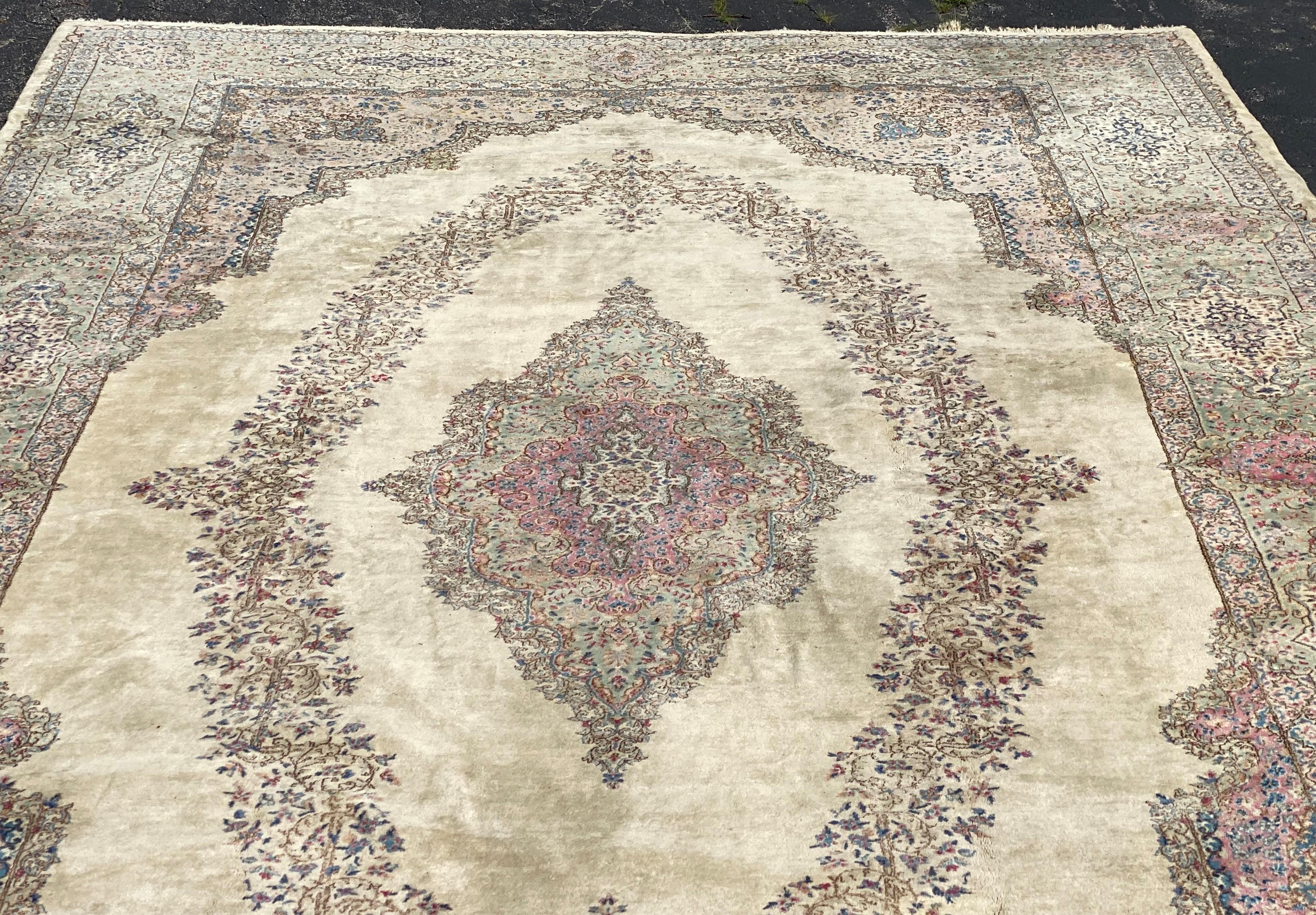 A fine large palace size Persian Lavar Kerman hand knotted rug with central diamond medallion and oval surround on a cream field with muted green,blue, and red foliate and scrolled border. Kerman has been a major center for the production of high