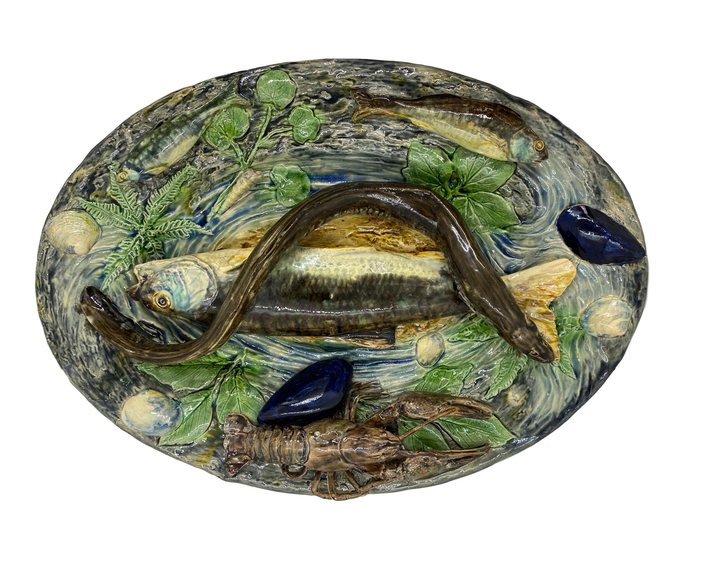 Grand plateau en trompe-l'œil en majolique de Plalissy par Alfred Renoleau (Français, 1854-1930), vers 1885.
Moulé de façon naturaliste d'un grand poisson et d'une anguille au centre, d'un homard et de divers petits poissons sur le bord, avec des