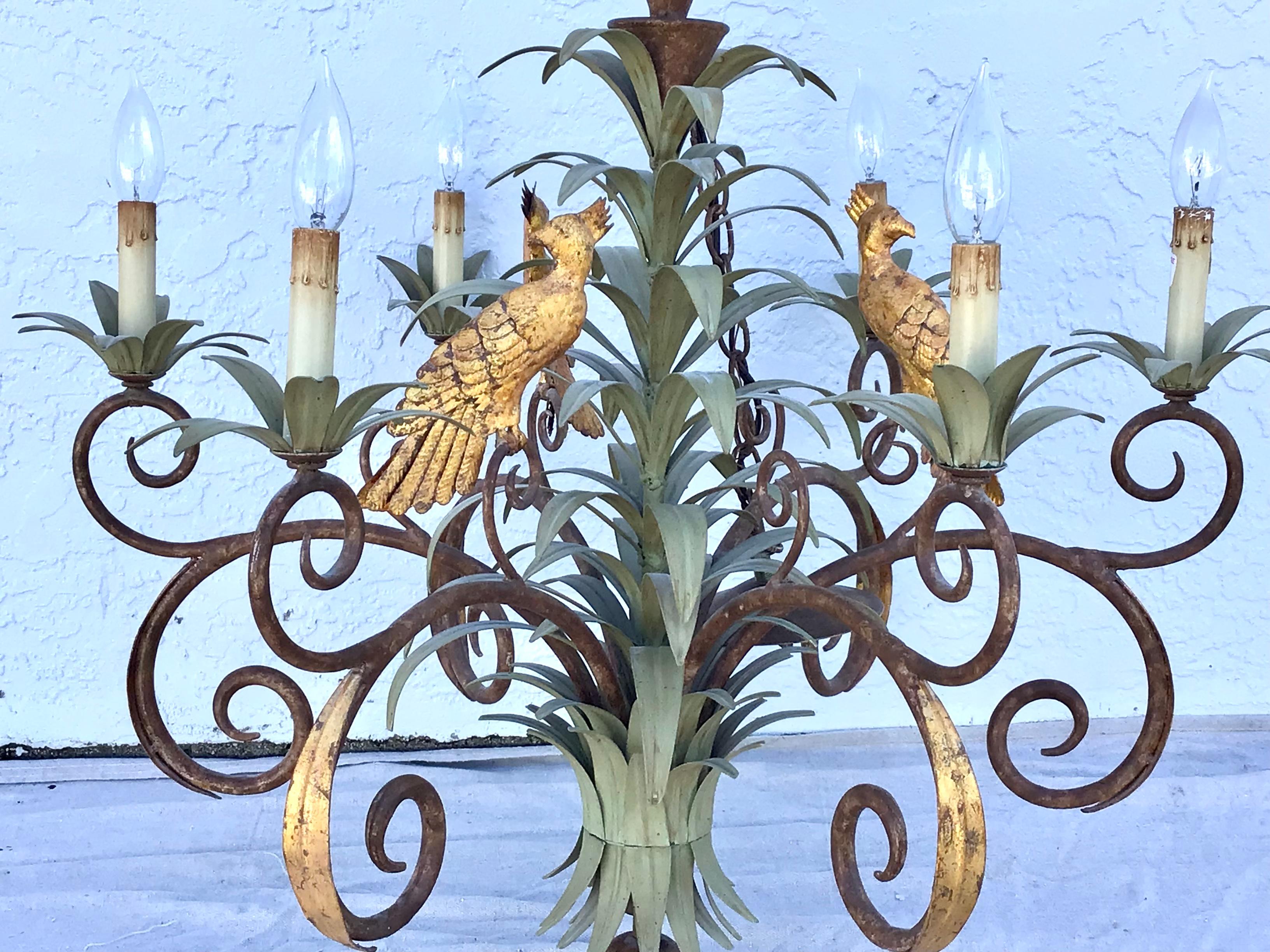 Palm leaf tole and gilt iron chandelier, 1960s. A beautiful chandelier featuring palm leaf stems with palm leaves and fronds throughout. Three gilt iron parrots resting on the palm leaves in the middle. There are 6 bulb holders.