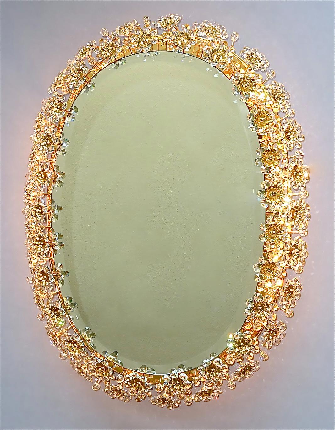 Large oval flower bouquet gilt brass metal crystal glass backlit wall mirror made by Palwa, Germany circa 1960-1970. The frame has lots of beautiful hand-cut faceted crystals in the shape of flowers or blossoms which sparkle like diamonds. The