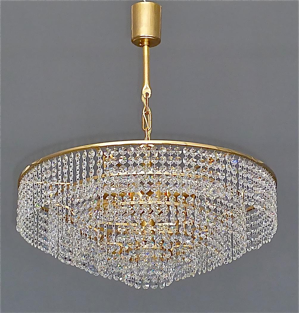 Classic large gilt brass and crystal glass chandelier made by high class lighting company Palwa, Germany, circa 1960. The chain-hanging chandelier has five cascading tiers with lots of high lead hand-cut faceted crystal glass strings which sparkle