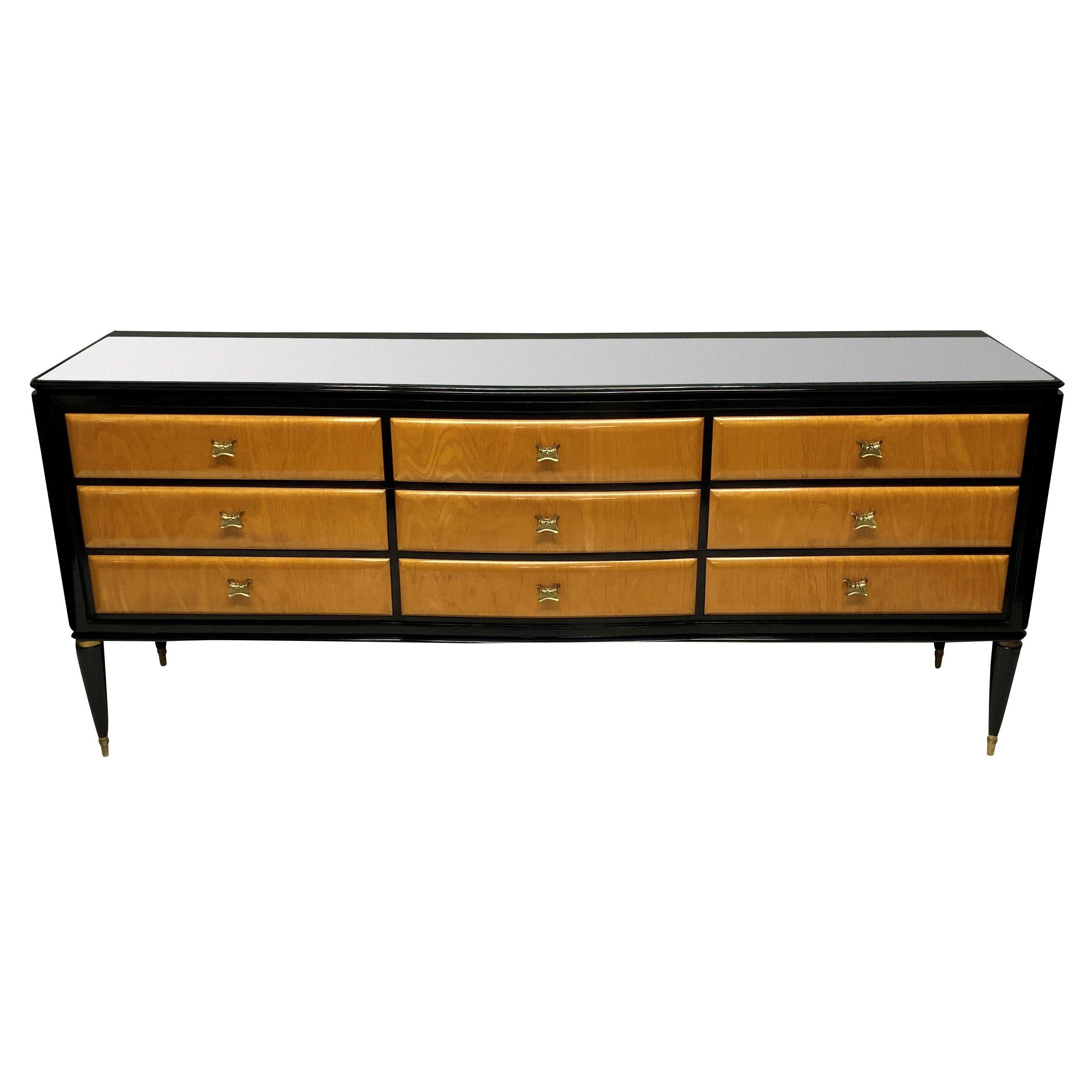 A large Italian credenza by Paolo Buffa in black lacquer, with lemon wood drawers. With nine drawers in total, each with a gilt brass handle, bras sabot feet and a mirror top with foliate etched border.