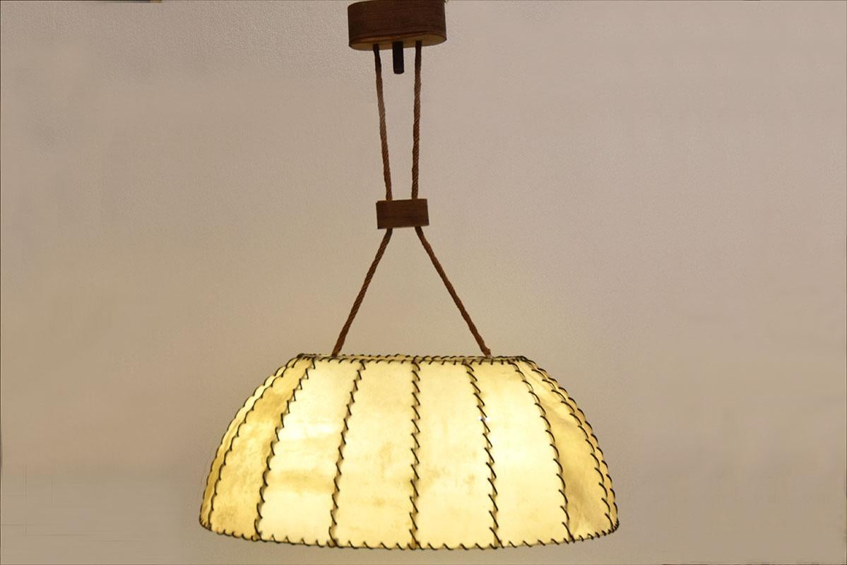 Large parchment chandelier made in Italy in the 1960s.
Oval diffuser in animal parchment with handmade leather stitching and hemp cords.
Wall support and tensioners covered in leather.
Original electrical system with 2 lamps.
In excellent