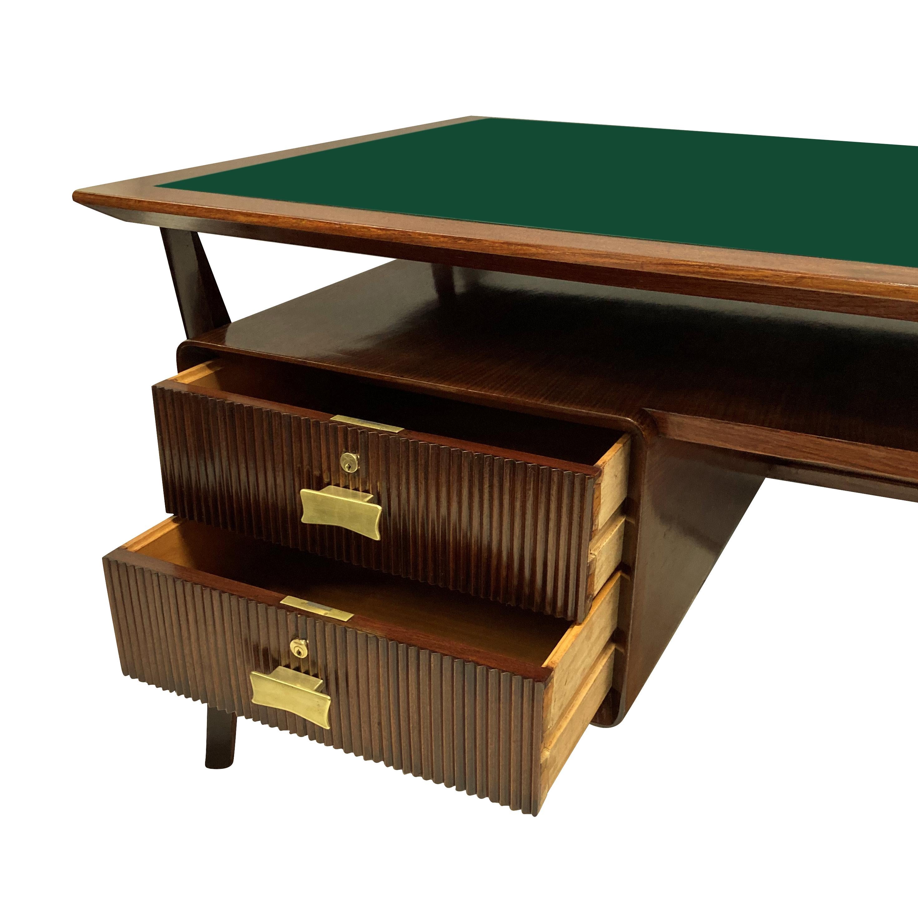 A large Italian walnut partners desk by Osvaldo Borsani, with four tambour fronted drawers with brass fittings and the original green glass top. The opening is 59cm high x 64cm wide.