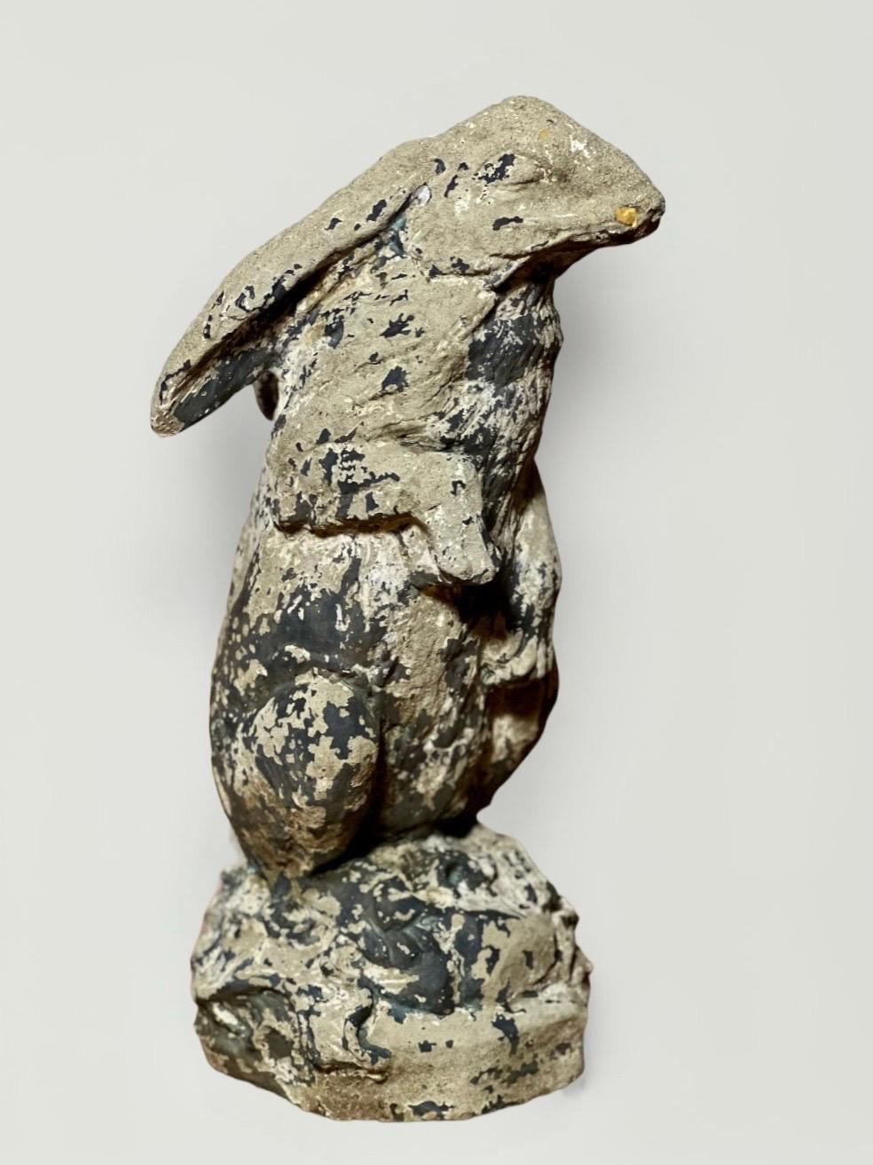 Charmante statue de jardin en ciment coulé, grandeur nature, représentant un lièvre anglais, avec une patine d'usage et des restes de peinture noire. Il a beaucoup de caractère avec une expression douce, de longues oreilles détendues et un