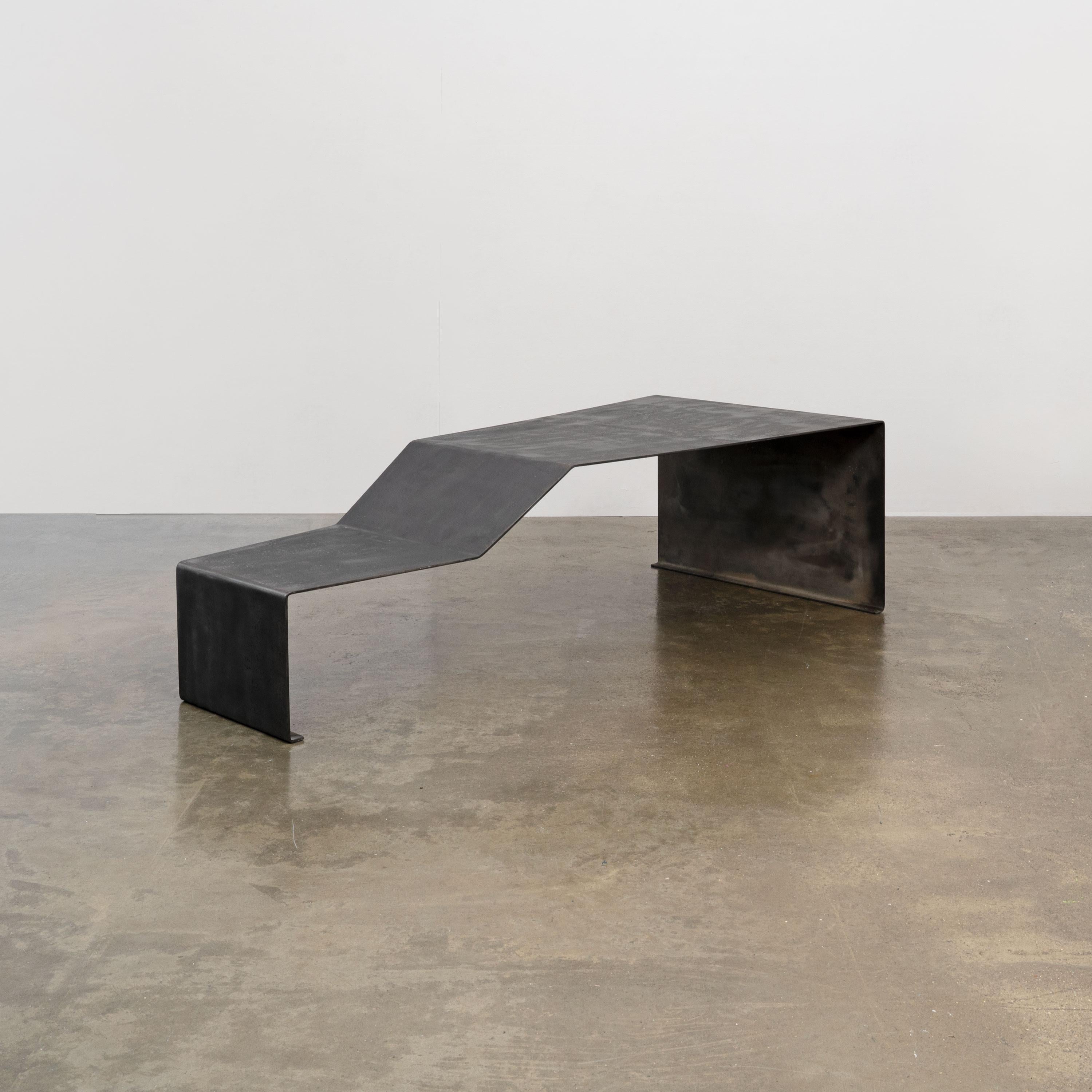 A large bench or coffee table made from a single piece of patinated bent steel. Of late 20th Century production. Handmade and likely one of a kind. 

Dimensions (cm, approx)
Height: 51
Width: 172
Depth: 80

Condition: Various superficial