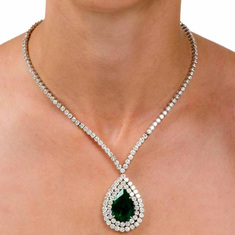 This  elegant necklace is crafted in solid 18K white gold.  Centered with a prominent faceted pear-shape emerald  weighing approx. 18.40 carats, surrounded by a two rows of diamonds. The eye-catching pendant suspends from the center of diamond
