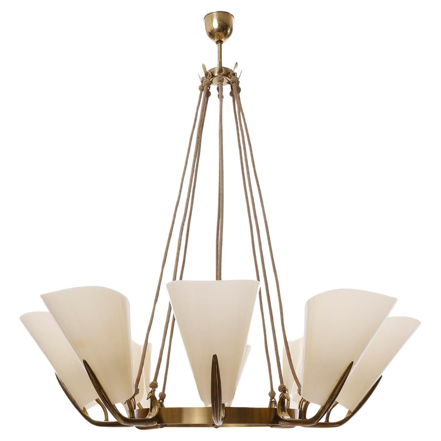 A fantastic and extra large 8-arm pendant chandelier manufactured in midcentury, crica 1960 (late 1950s or early 1960s).
The light fixture is made of a solid, polished brass frame with curved arms suspended on cords from the ceiling canopy.
A high