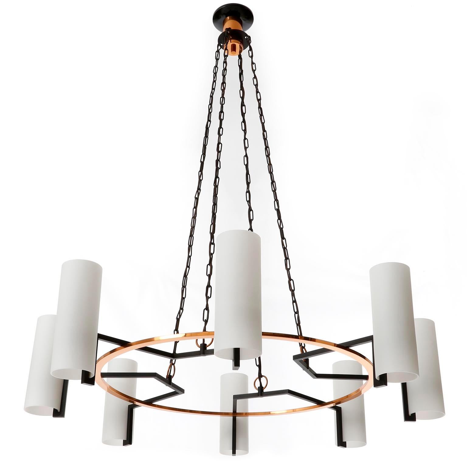 A large pendant chandelier manufactured in midcentury, circa 1970 (late 1960s or early 1970s).
This geometric shaped fixture is made of a polished copper ring with little patina and black painted metal arms with cylindric opaline glass lamp shades.